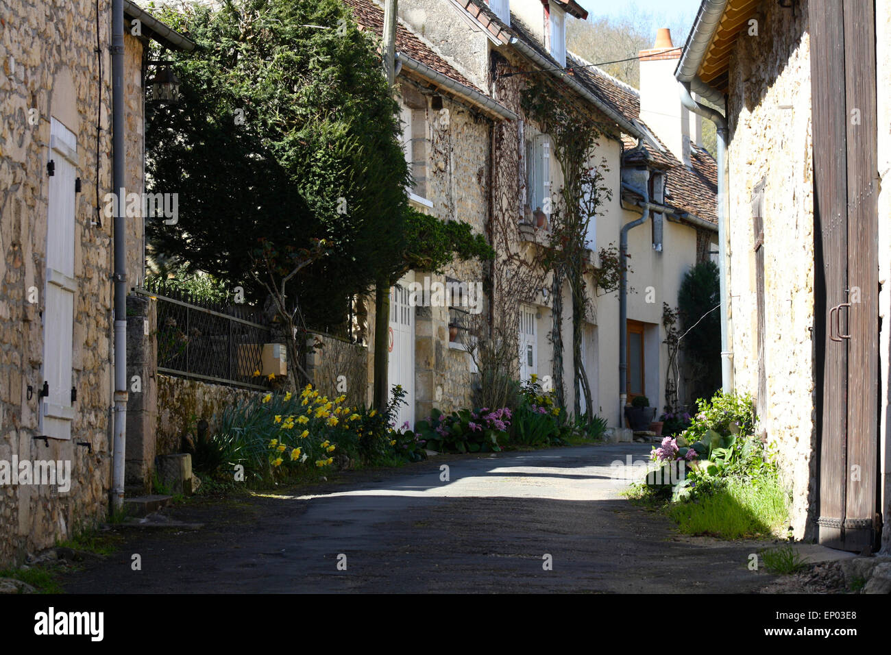 Antico villaggio francese street con fila di pittoreschi cottage in pietra in ombra parziale e dalla luce diretta dei raggi solari. Foto Stock