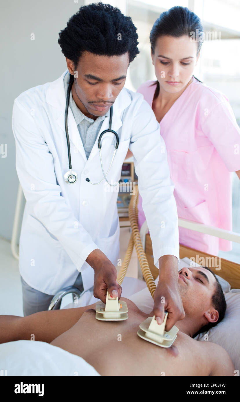 Medico etnici utilizzando un defibrillatore su un paziente Foto Stock