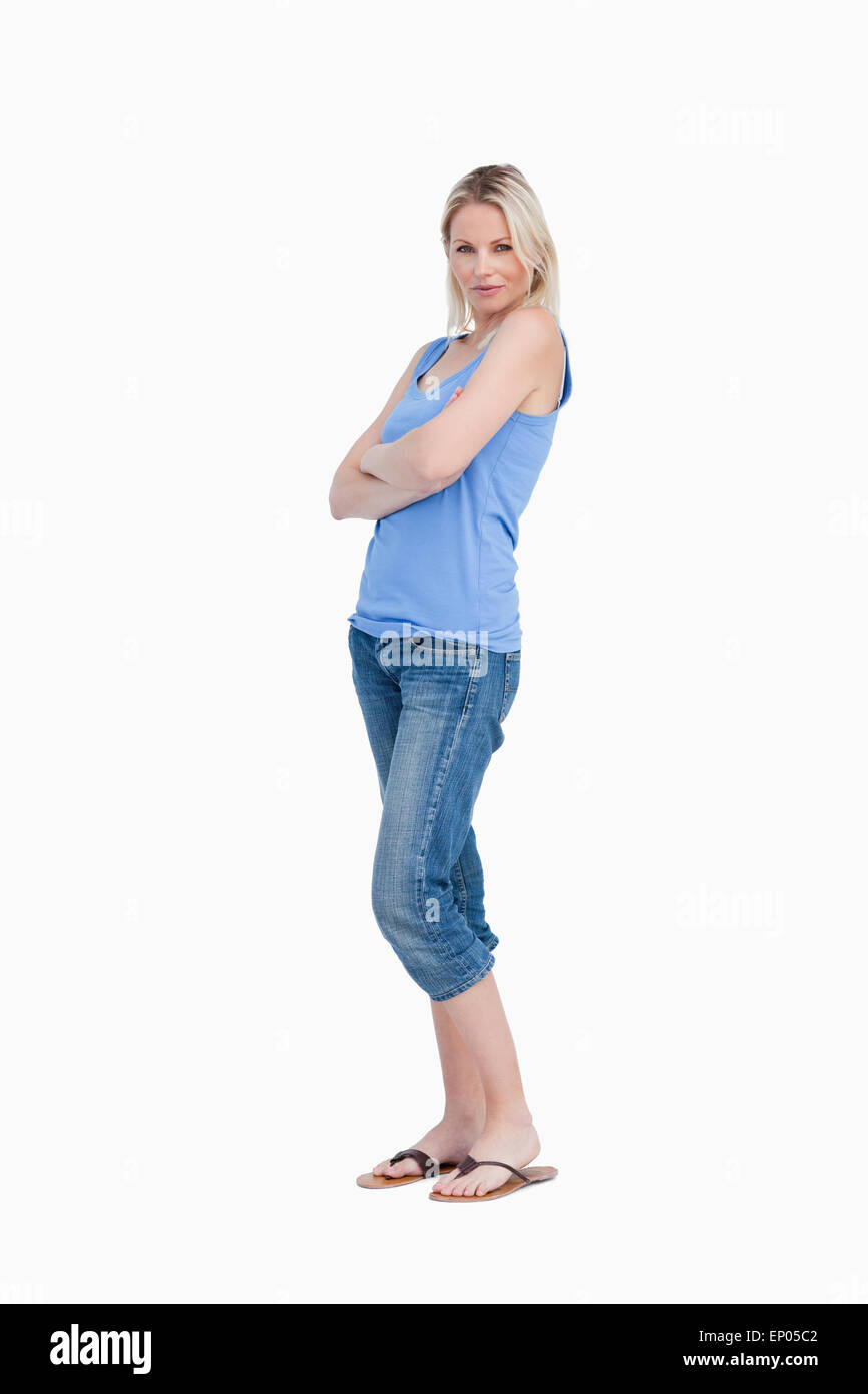 Rilassata giovane donna in posizione eretta con le braccia incrociate Foto Stock