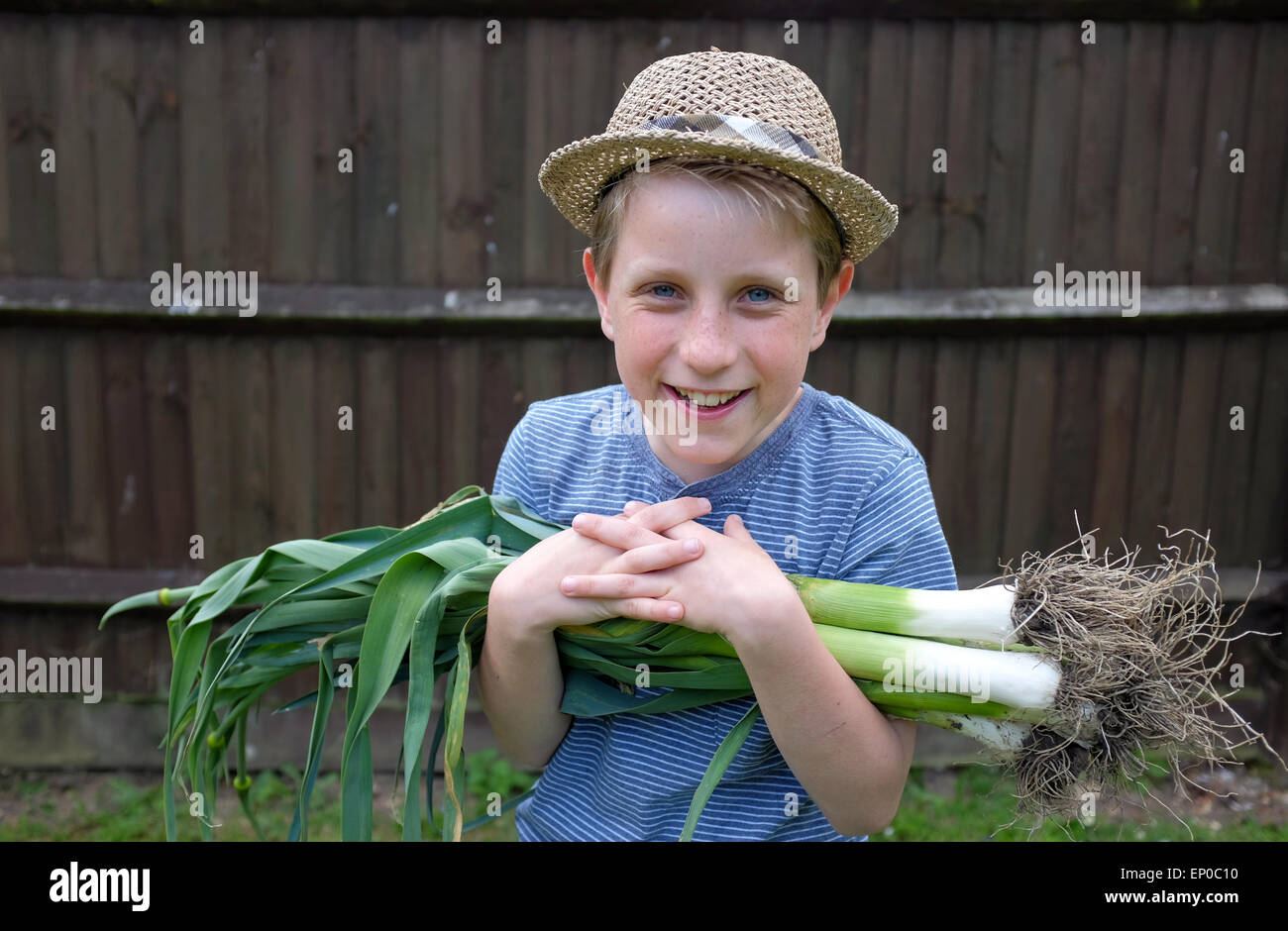 Un ragazzo felice con freschi coltivati i porri organico prelevato dal giardino Foto Stock
