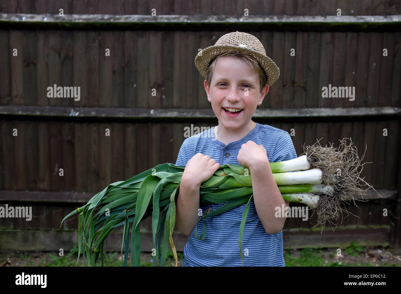 Un ragazzo felice con freschi coltivati i porri organico prelevato dal giardino Foto Stock