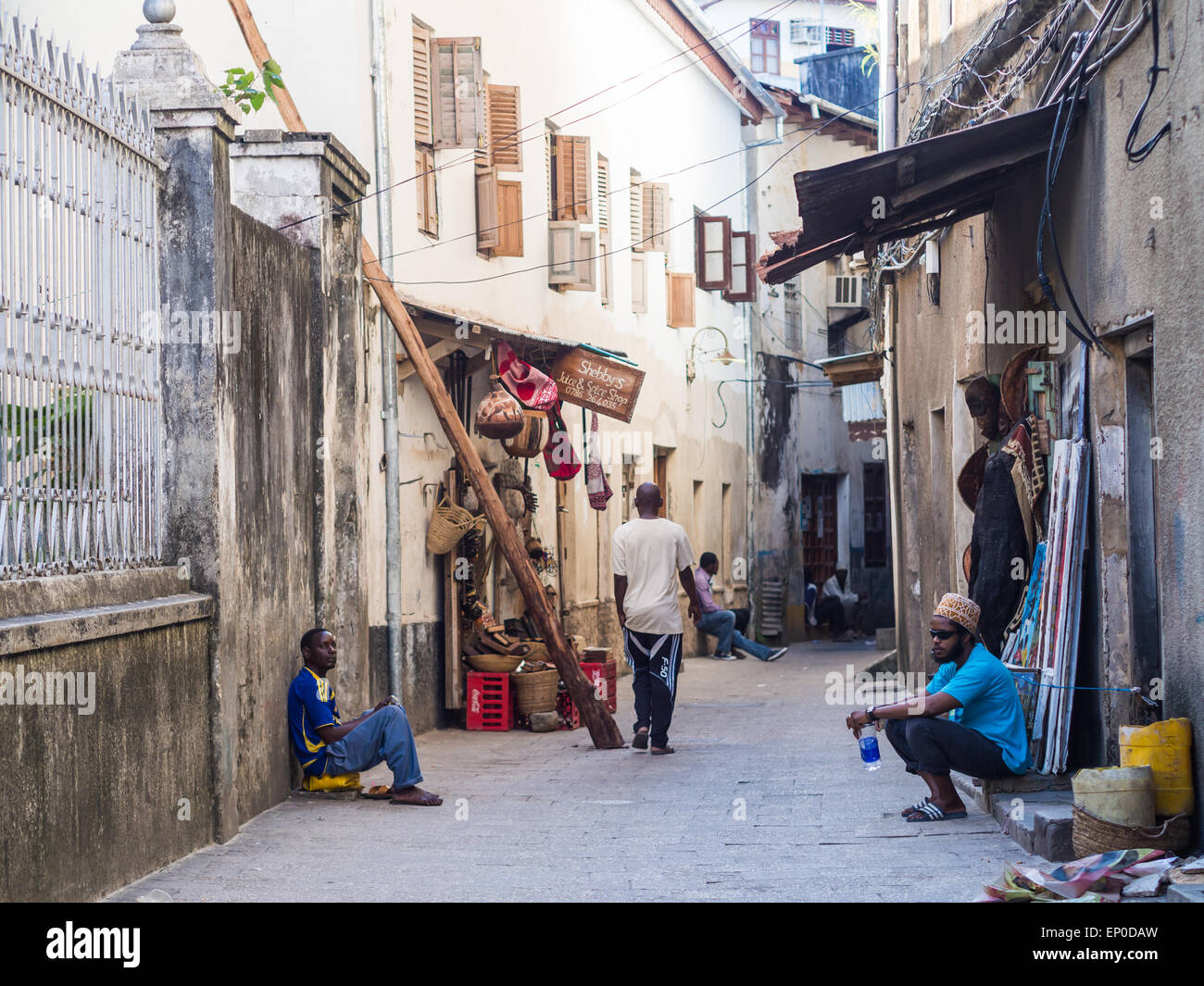 La popolazione locale a camminare su una delle strade strette nella parte vecchia della città di pietra, Zanzibar in Africa orientale. Orientamento orizzontale Foto Stock