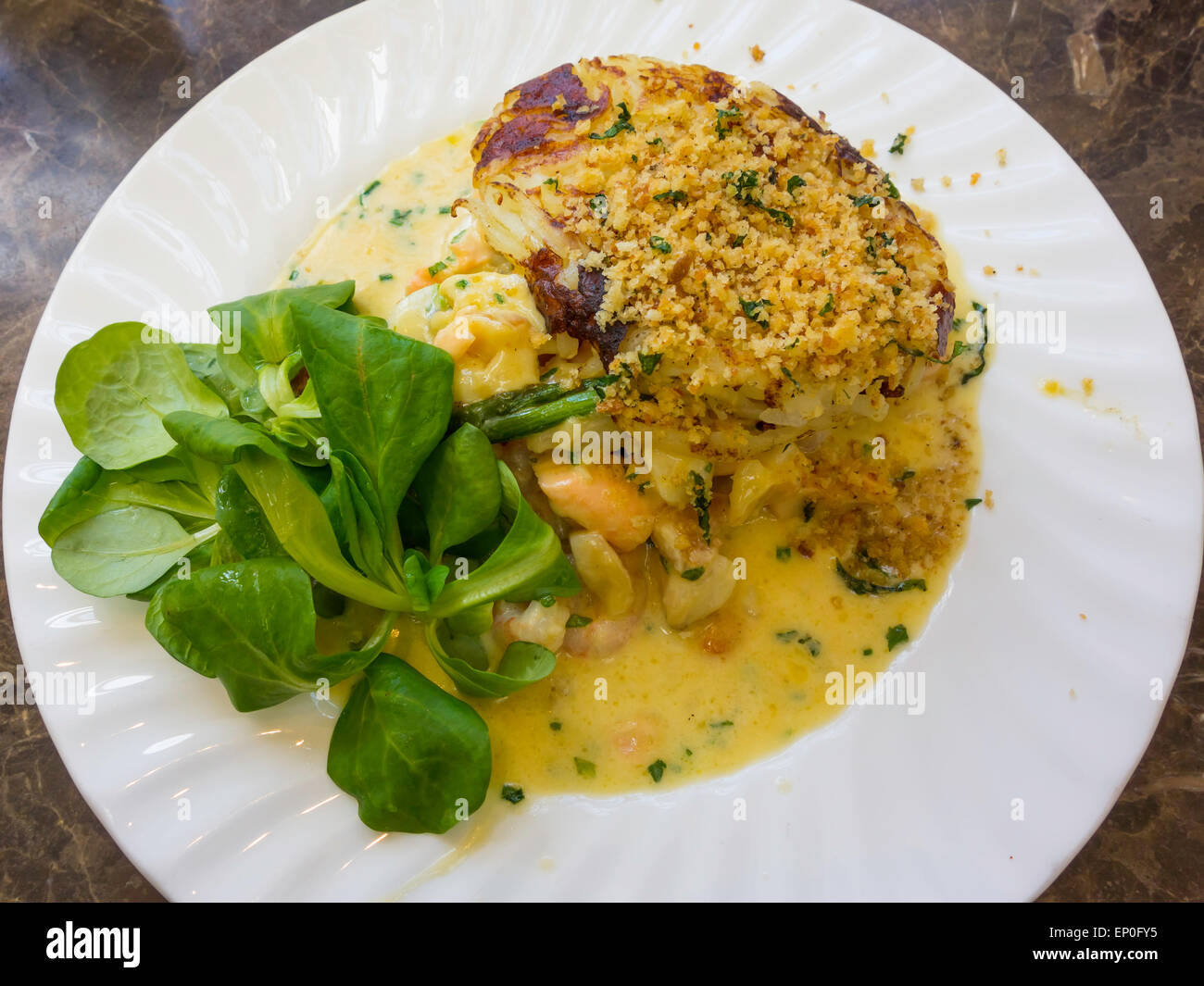 Il pranzo, eglefino salmone e gratin di gamberi in salsa di vino bianco su appassì spinaci con patate röstinchen e condito breadcrumb topping Foto Stock