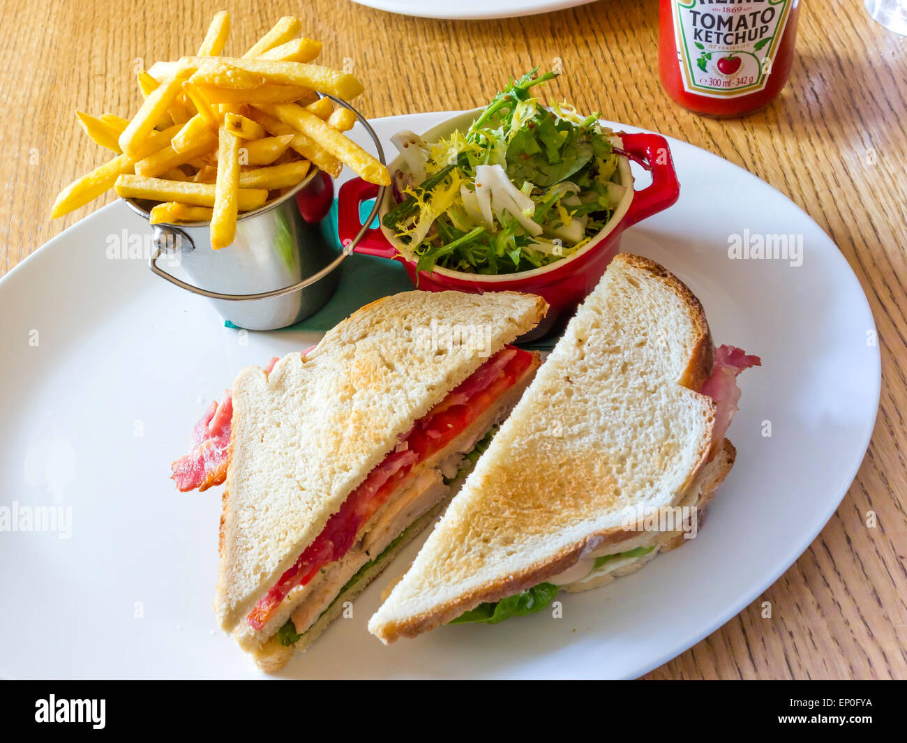 Café il pranzo a due- strato club sandwich di pane bianco con pancetta insalata di pollo al pomodoro e mayo con insalata e patatine fritte Foto Stock