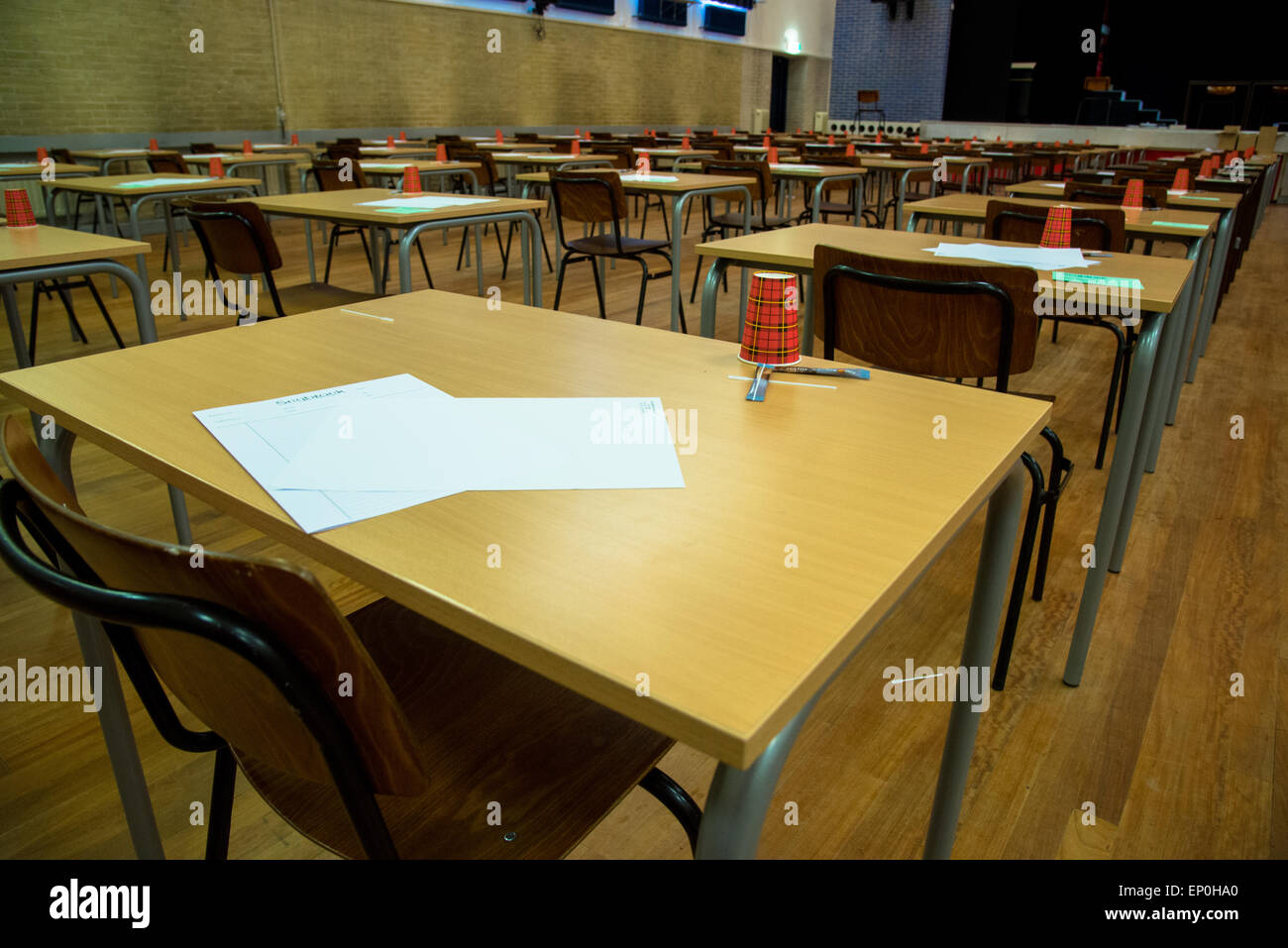 Fila di tavoli e sedie con carta e tazze di attesa per l'esame di highschool Foto Stock
