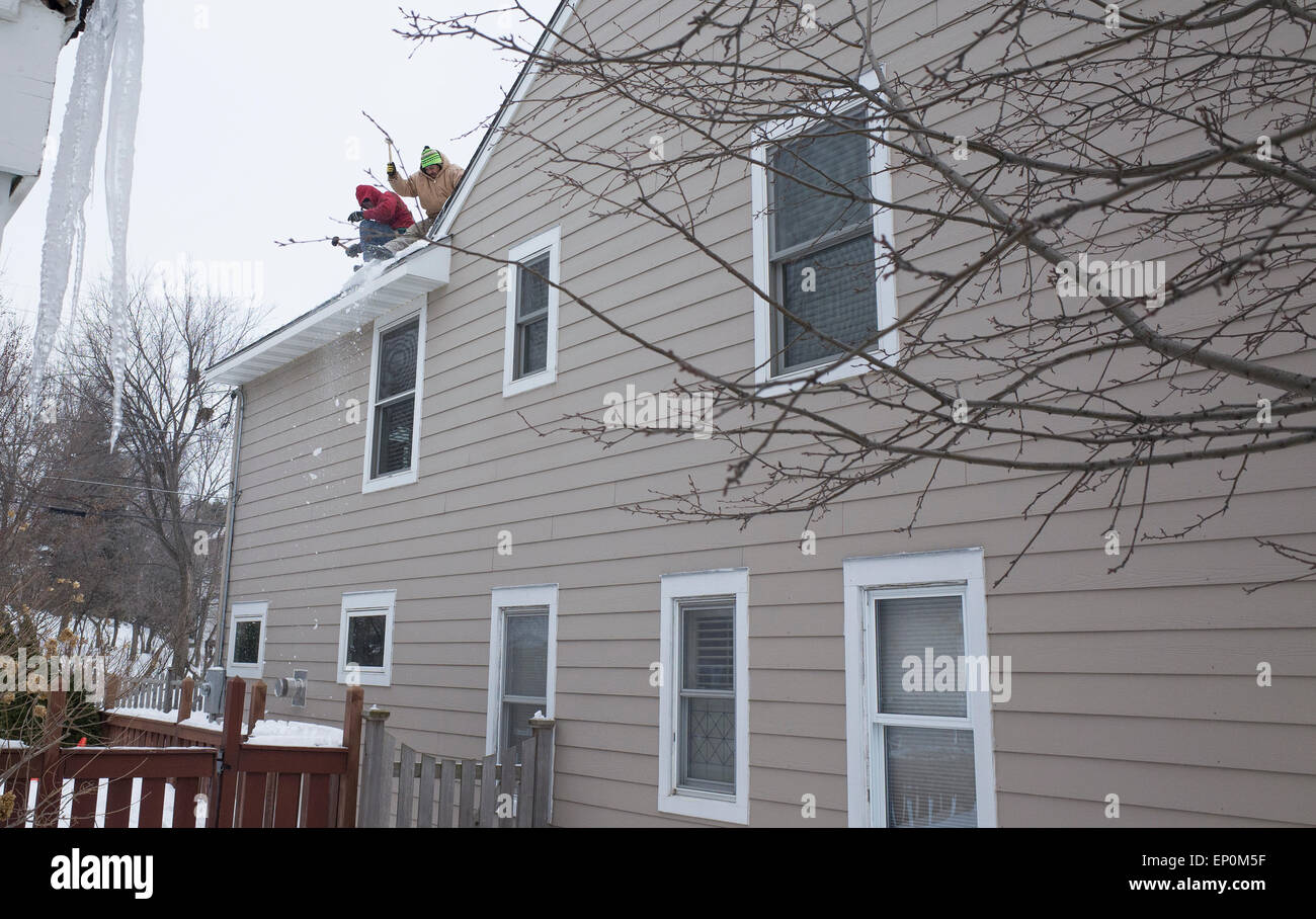 Lavoratori ispanica la rimozione di neve e ghiaccio da tetto per prevenire la schiacciante di ghiaccio e la perdita di acqua in casa. St Paul Minnesota MN USA Foto Stock