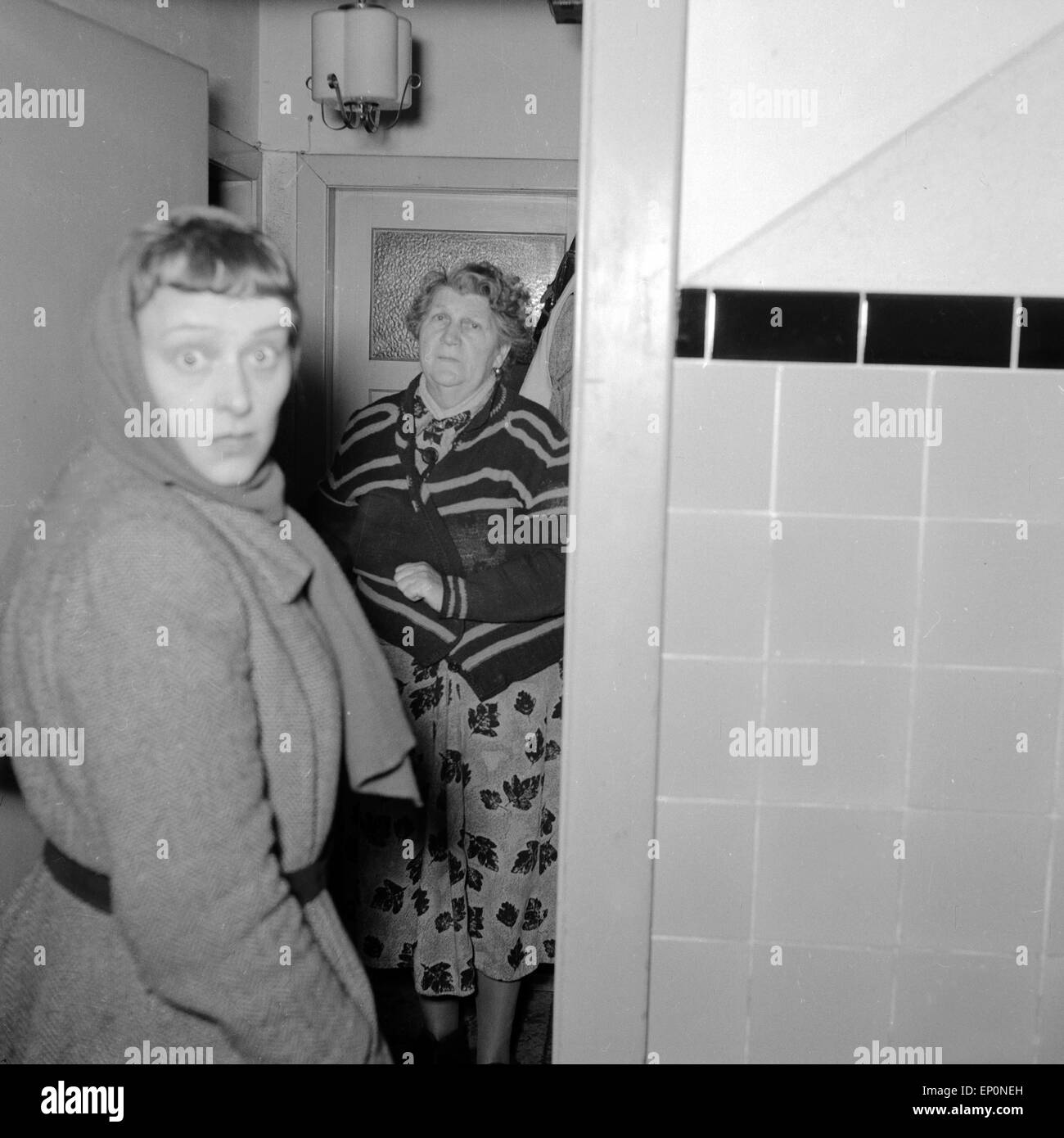 Zwei Frauen unterhalten sich in einem Treppenhaus und werden von der Kamera überrascht, Amburgo 1954. Due donne in chat con il Foto Stock