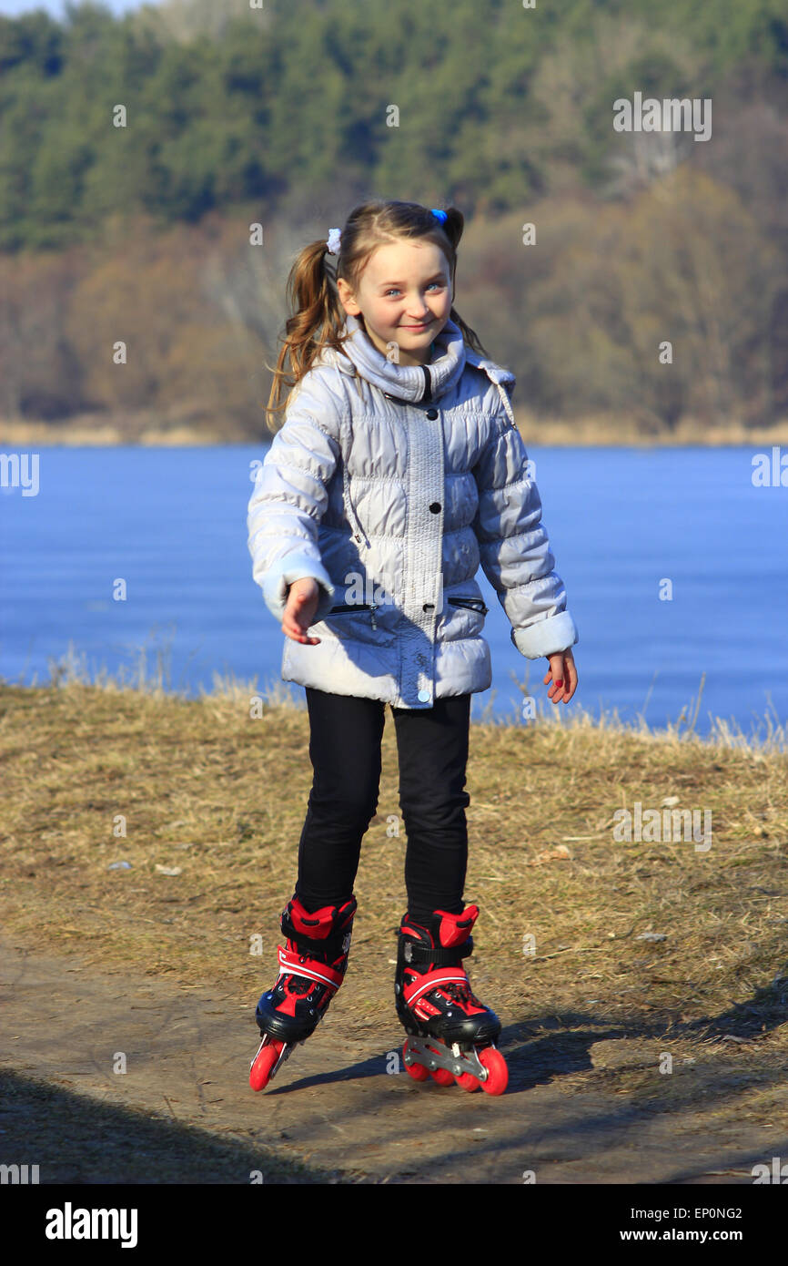 Giovane bella ragazza va in pattini a rotelle sul terreno Foto Stock