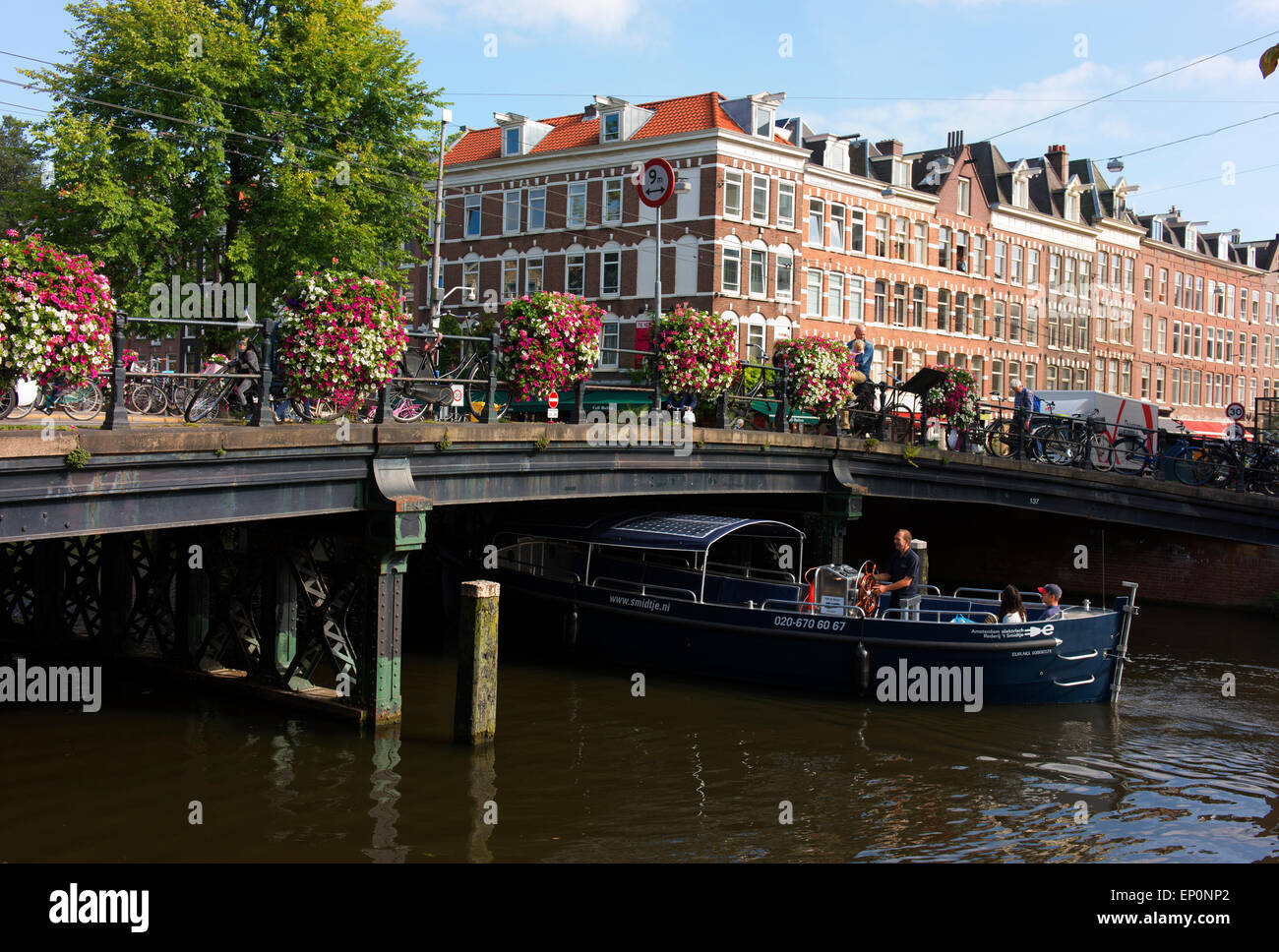 Barca tradizionale con i turisti passa sotto un ponte nel centro di Amsterdam. Foto Stock