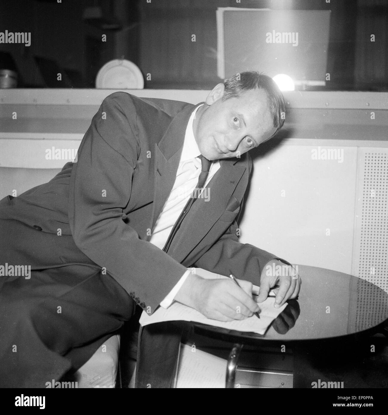 Ein Mann hängt unbequem über einem Tischchen, um sich Notizen zu machen, Amburgo 1954. Un uomo seduto in un grande modo invconvenient Foto Stock