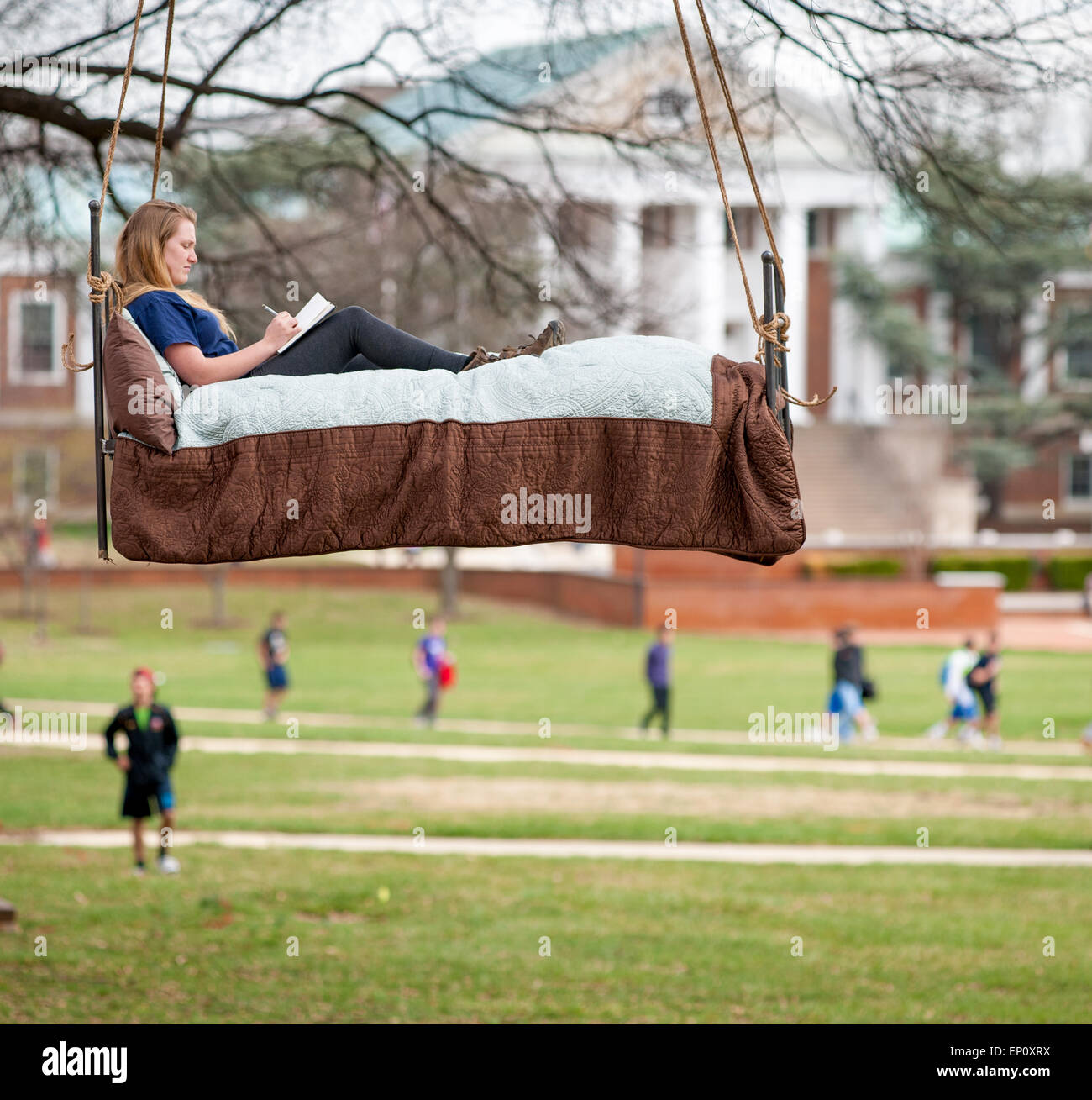 Un progetto artistico che mostra una giovane donna facendo i compiti su un letto appeso a un albero a College Park, Maryland Foto Stock