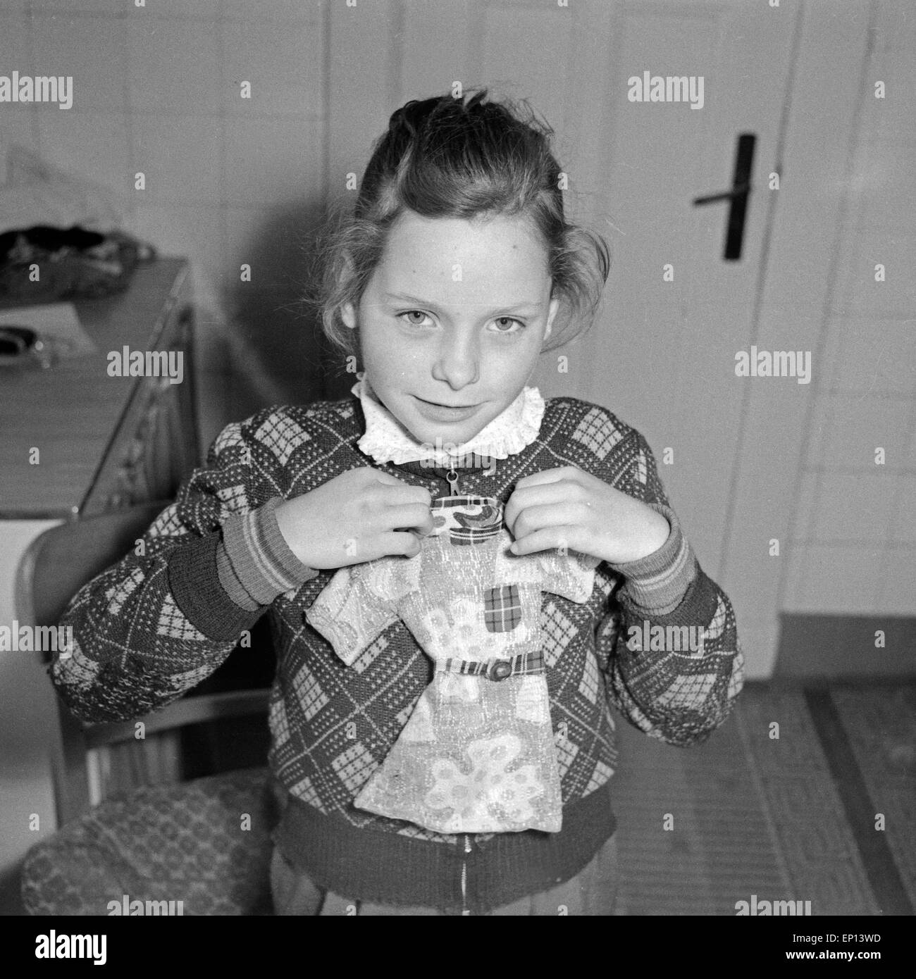Ein kleines Mädchen präsentiert stolz ein selbst geschneidertes Puppenkleid für Ihre Puppe, Deutschland 1950er Jahre. Un po' di g Foto Stock