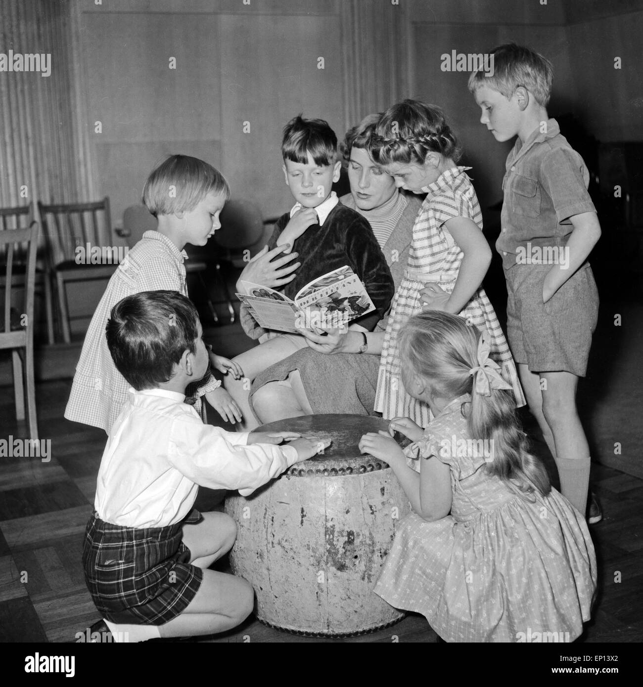 Eine Kindergärtnerin liest ihrer Gruppe aus dem Pixi Buch vom Elefanten Puff Puff Pata vor, Deutschland 1950er Jahre. Un kinderga Foto Stock
