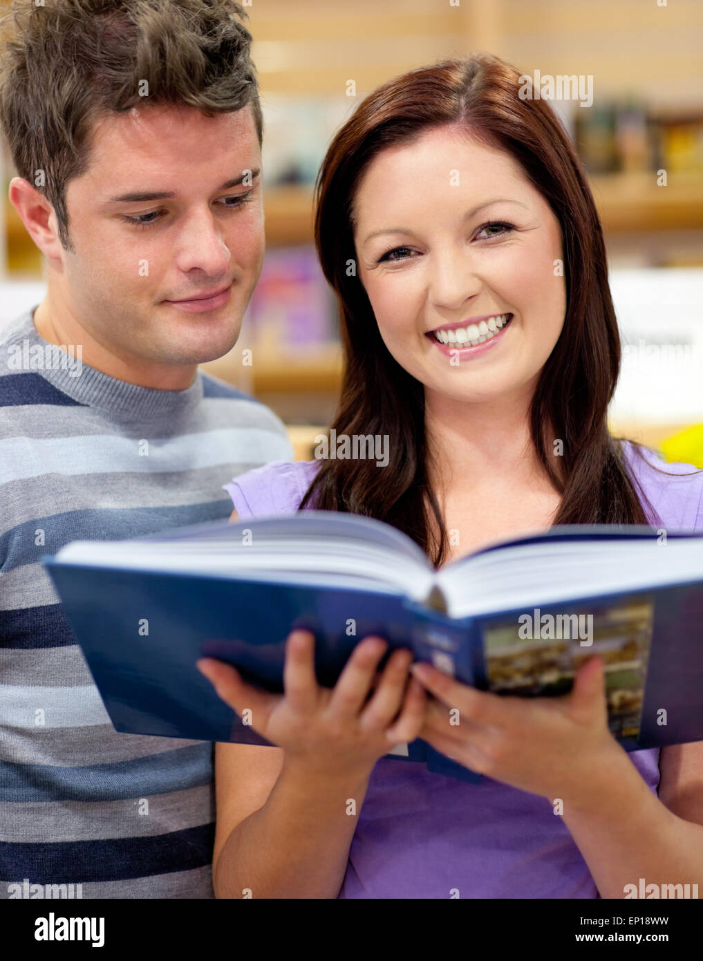 Luminose paio di studenti la lettura di un libro in una libreria Foto Stock