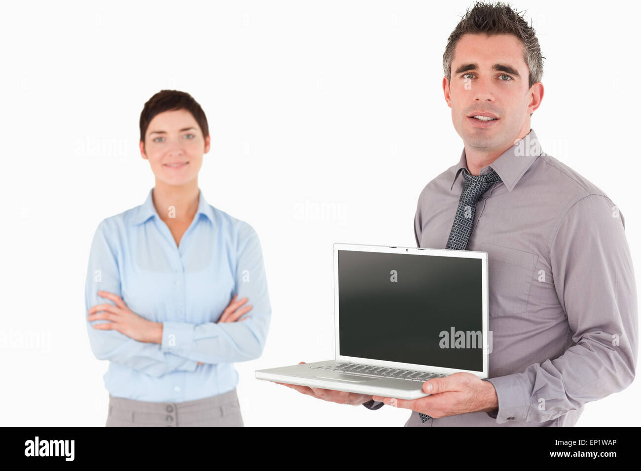 Lavoratore di ufficio che mostra un computer portatile mentre il suo collega è in posa Foto Stock