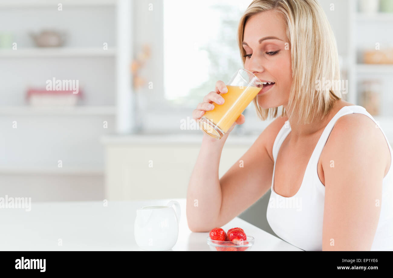 Donna seduta ad un tavolo a bere un succo di arancia Foto Stock
