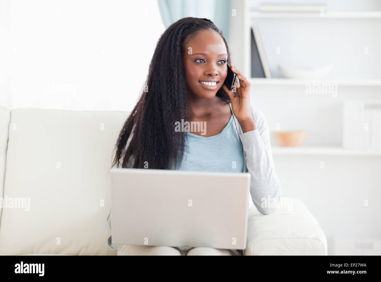 Donna con lo smartphone e il computer portatile sul divano Foto Stock