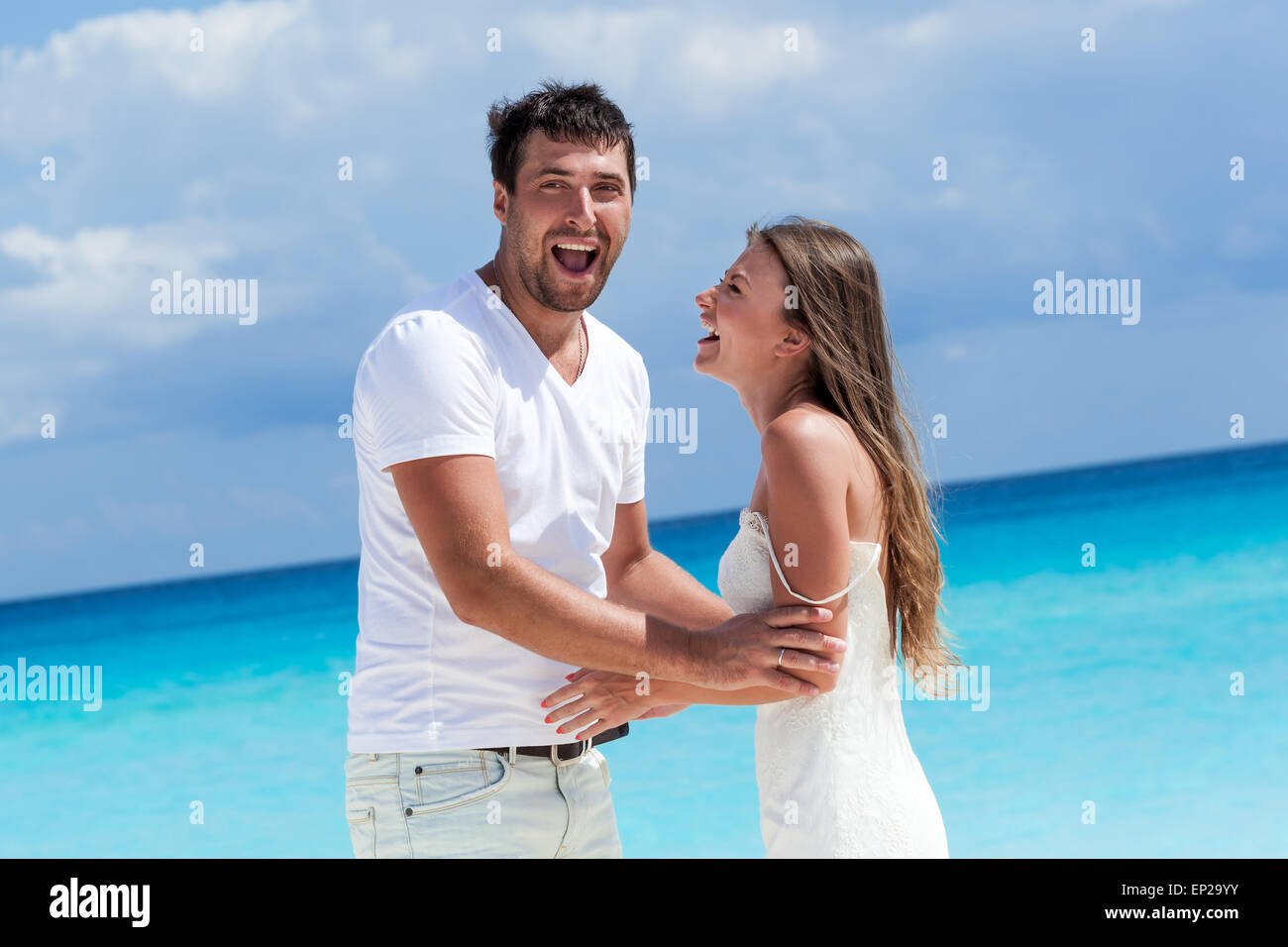 Sorridenti sposi novelli avendo divertimento sulla spiaggia, godendo di vacanza tropicale Foto Stock