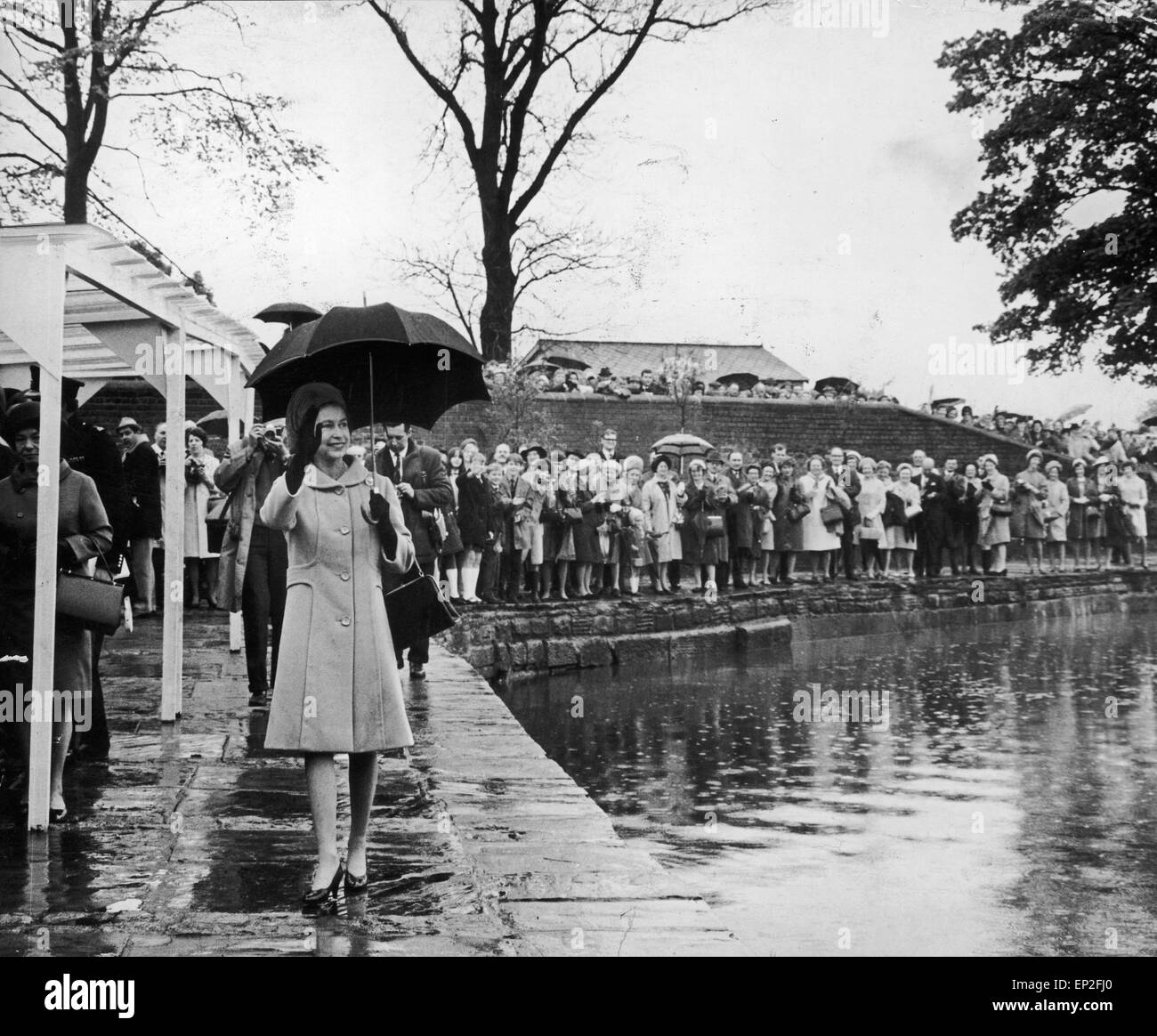 La regina visita Manchester. Verso il basso mediante il Waterside la regina onde da sotto il suo ombrello per la corona in attesa sul ponte a Marple come lei cammina dalla pioggia-spruzzato sulle canal. 16 maggio 1968. Foto Stock