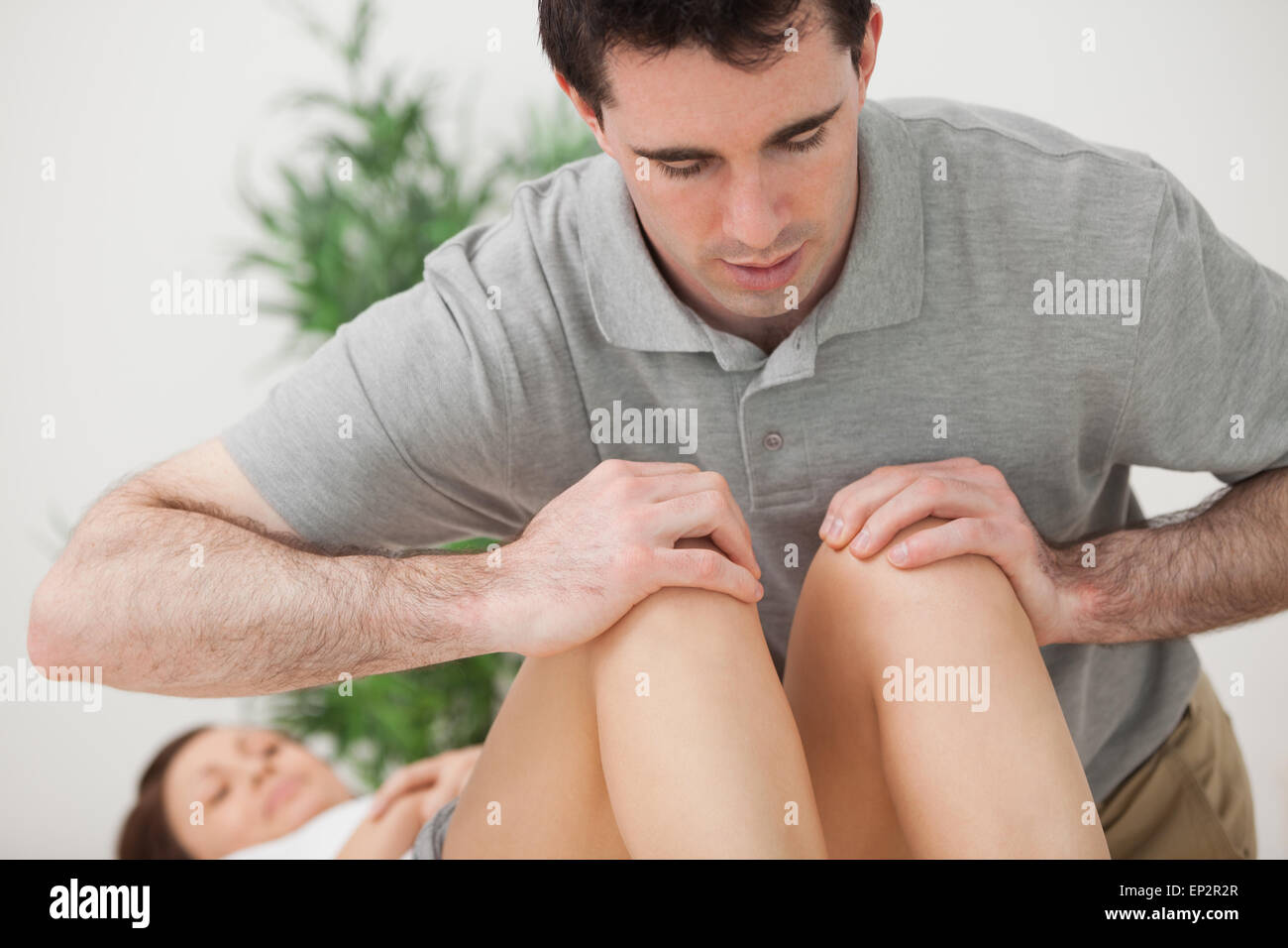 Medico grave premendo sulle ginocchia di un paziente Foto Stock