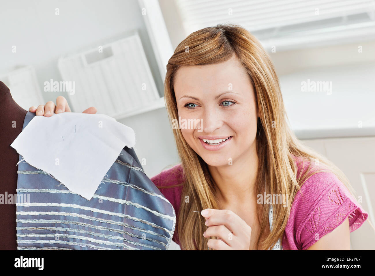 Positivo giovane donna abiti da cucire a casa Foto Stock