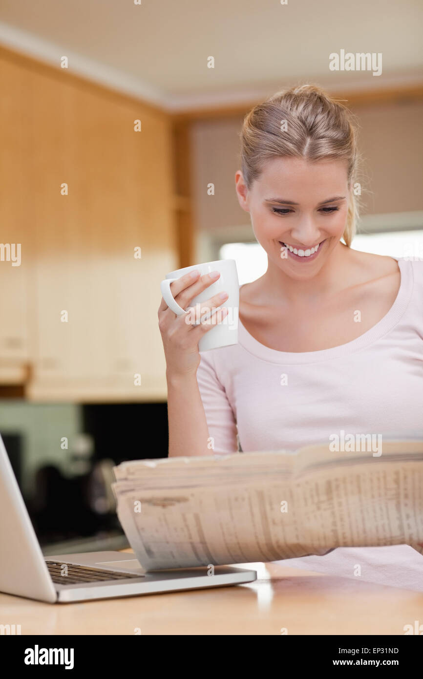 Ritratto di una donna la lettura di notizie pur avendo tea Foto Stock