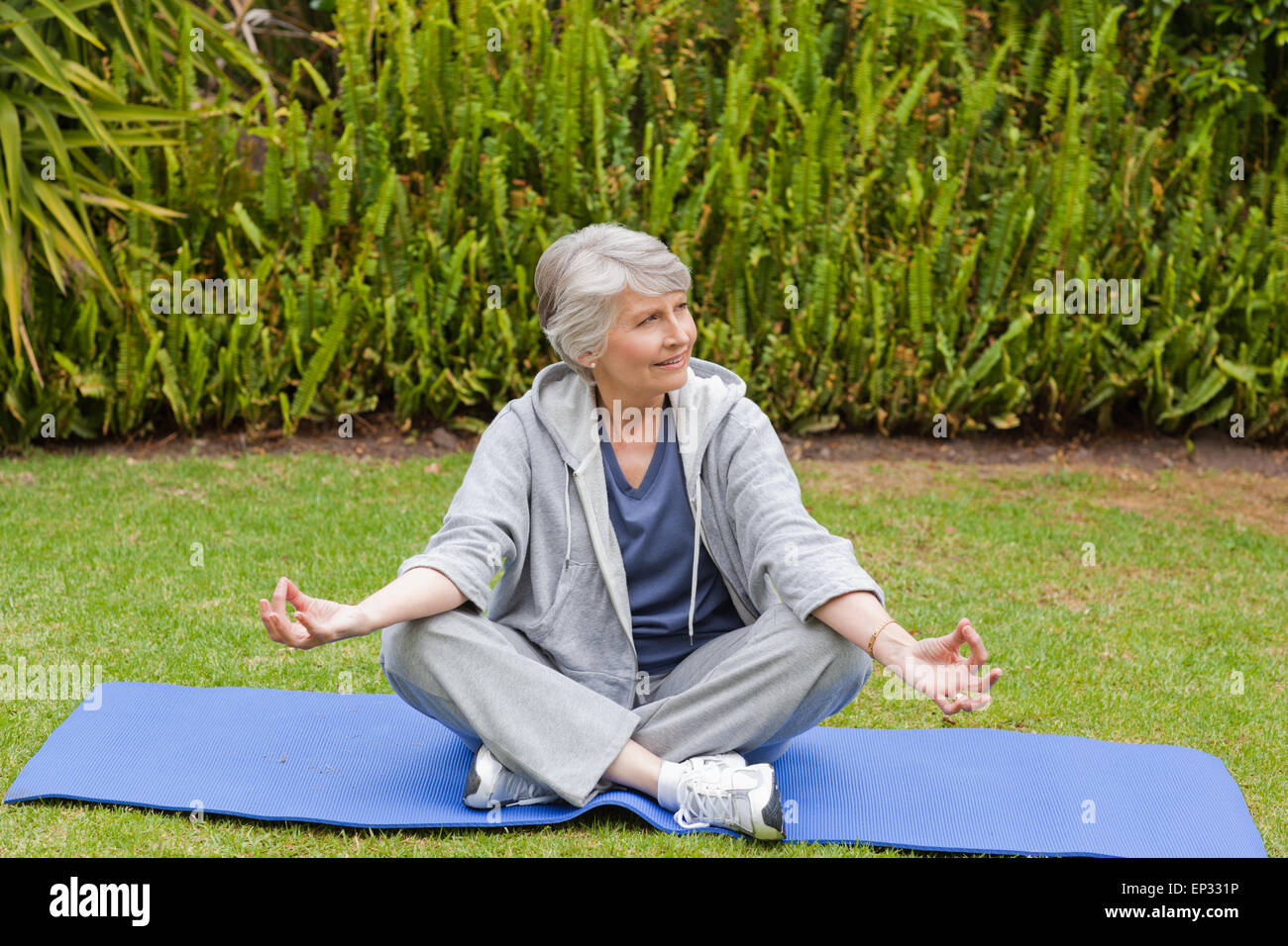 Donna in pensione a praticare yoga in giardino Foto Stock