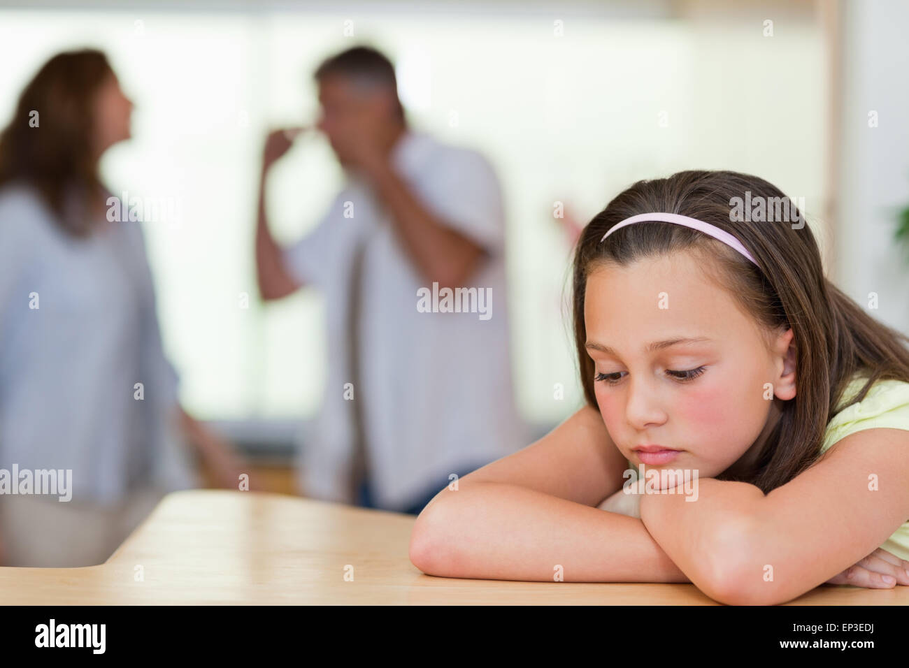Ragazza triste con la sua lotta contro i genitori dietro di lei Foto Stock