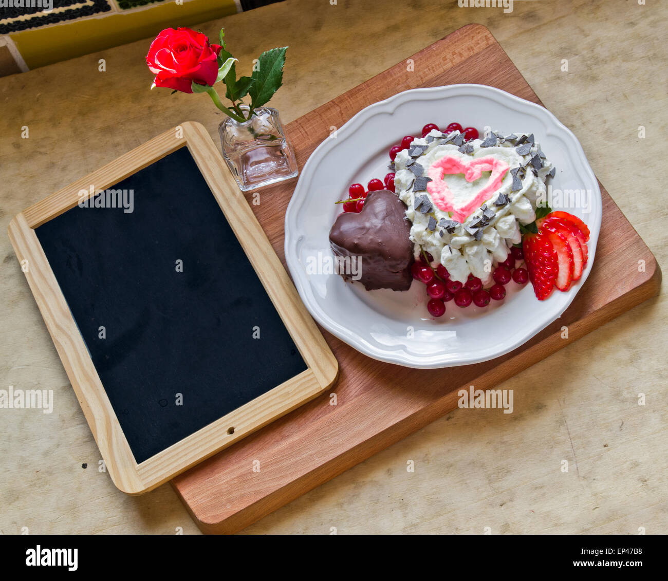 A forma di cuore ad un dessert con una rosa e una lavagna Foto Stock