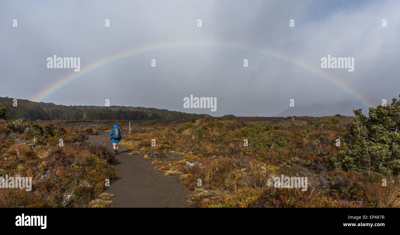L'uomo escursionismo verso un arcobaleno, Tongariro National Park, North Island, Nuova Zelanda Foto Stock