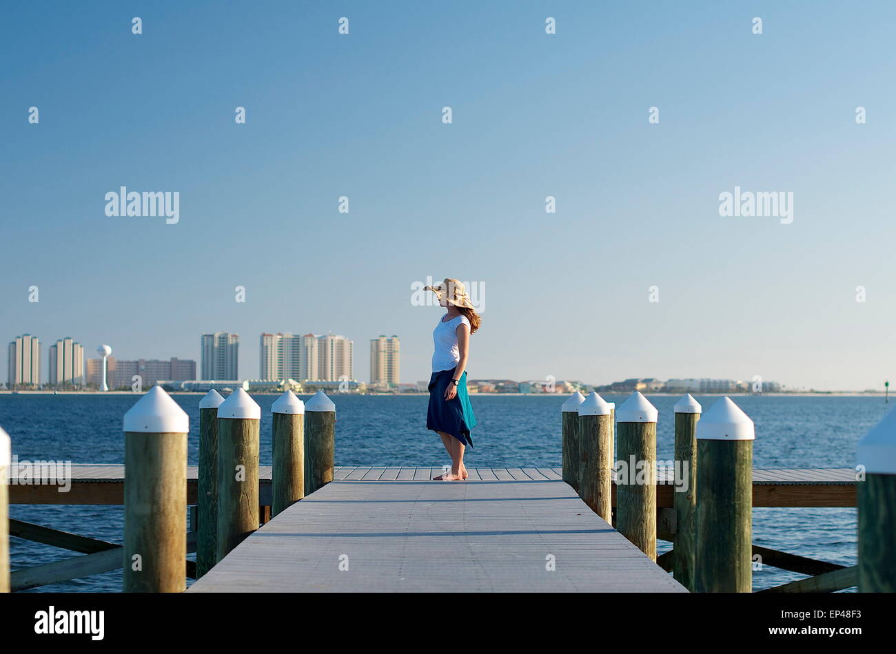 La donna nel cappello per il sole in piedi alla fine di un molo, Florida, Stati Uniti d'America Foto Stock