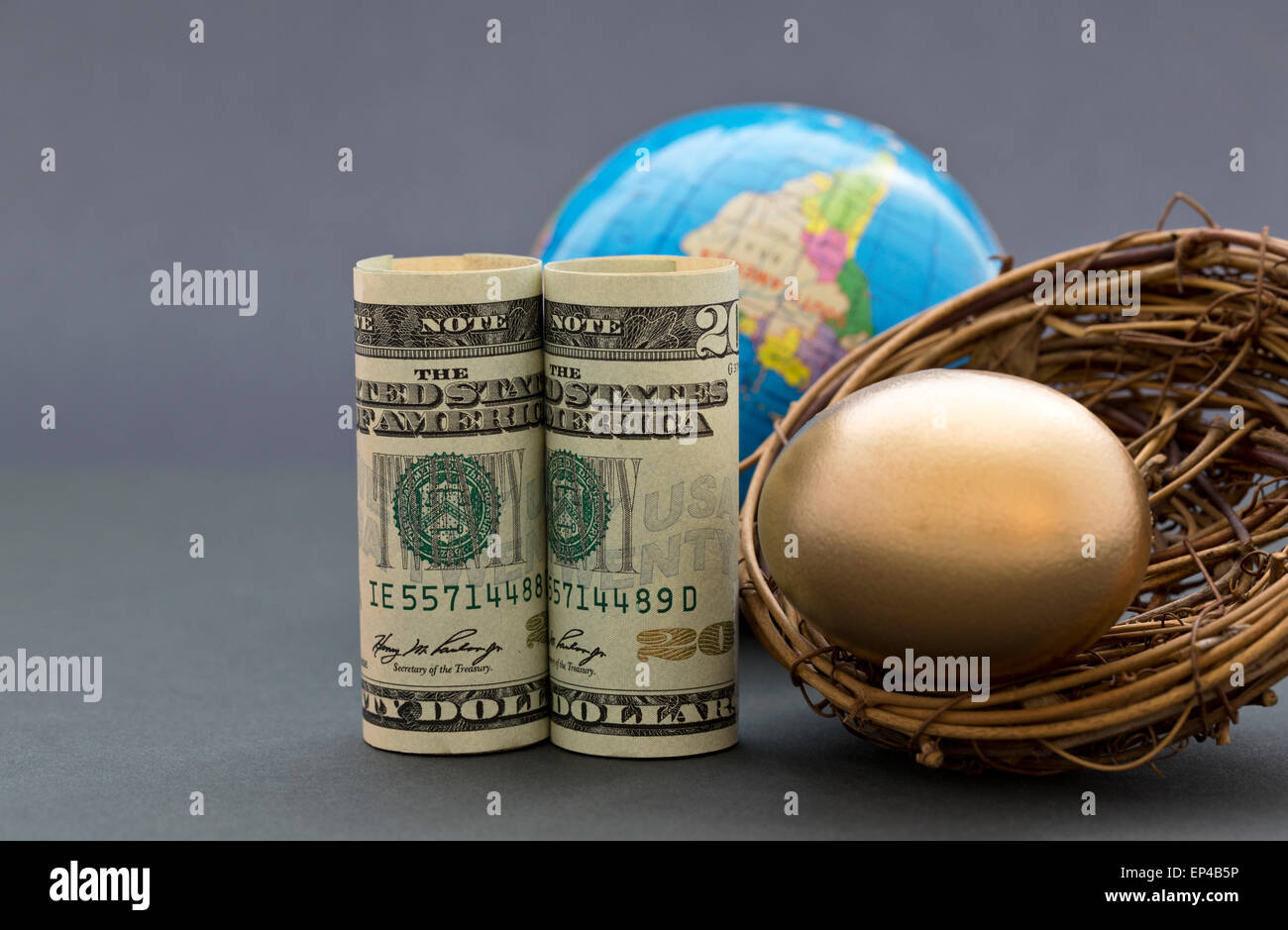 Dollari americani e oro uovo di nido con globo nella sofisticata e sfondo grigio. Foto Stock