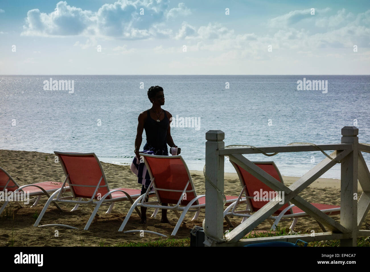 An African American boy saluta l'alba per un inizio di nuotare sulla spiaggia di castelli di sabbia su St. Croix, U.S. Isole Vergini. Foto Stock