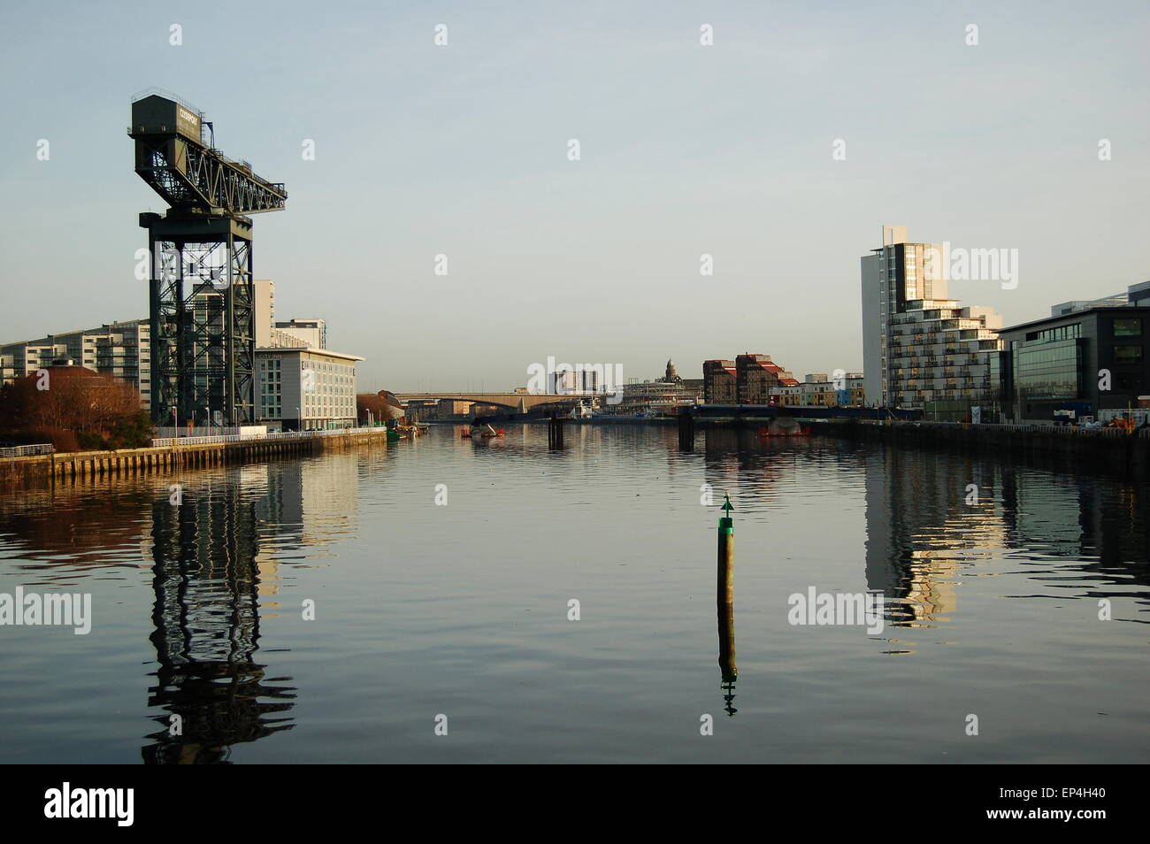 Una vista del fiume Clyde a Glasgow, in Scozia. Edifici e una gru riflettere nel fiume. Foto Stock