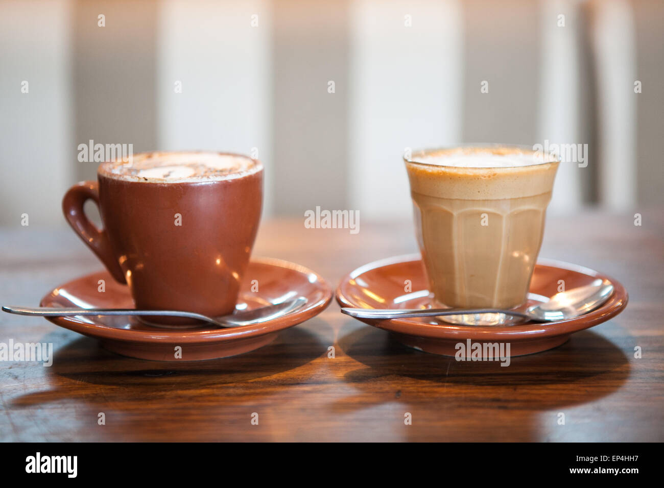 Due caffè seduti a un tavolo con un sfondo striato. Foto Stock
