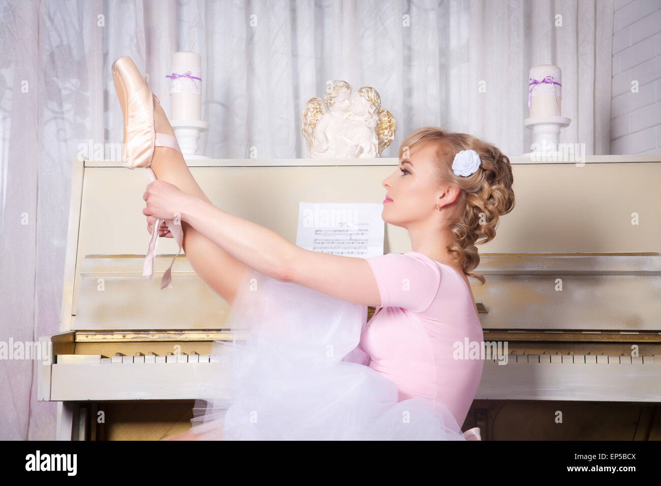 Ballerina in pointe shoes seduto su una sedia vicino al pianoforte Foto Stock