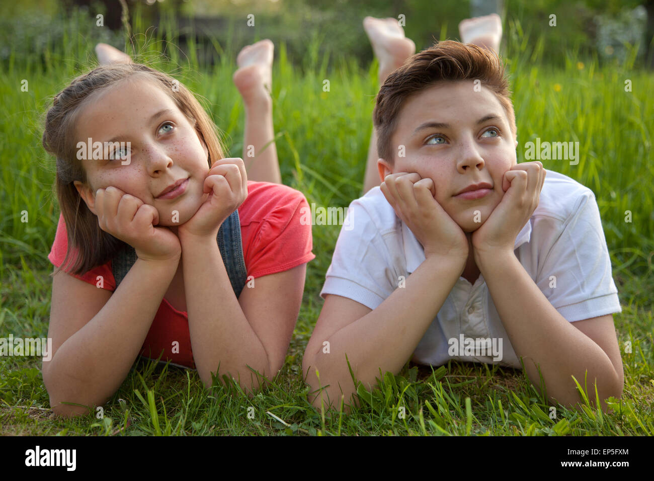 Mädchen und Junge träumen auf einer Wiese Foto Stock