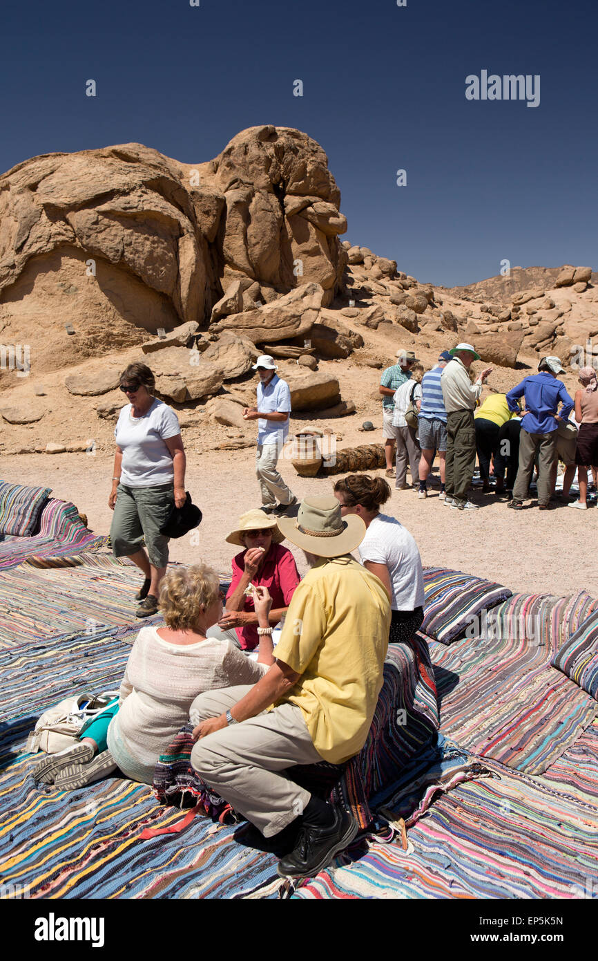 L'Egitto, il Sinai beduini Desert Camp, turisti sat su tappeti di mangiare pane piatto Foto Stock