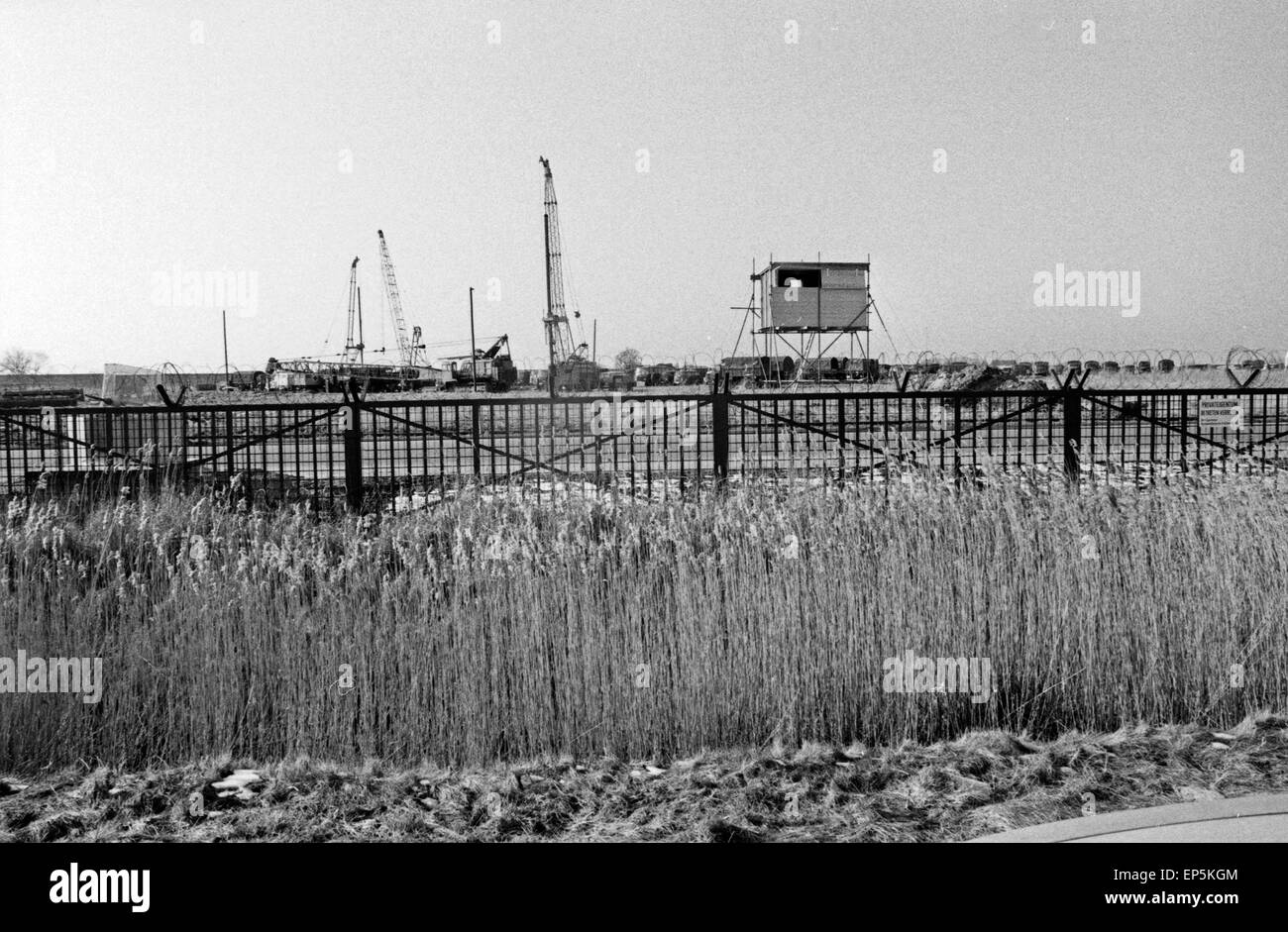 Polizeieinsatzwagen sichern die Baumaschinen hinter dem Zaun des Kernkraftwerks in Brokdorf, Deutschland 1980er Jahre. La polizia tr Foto Stock