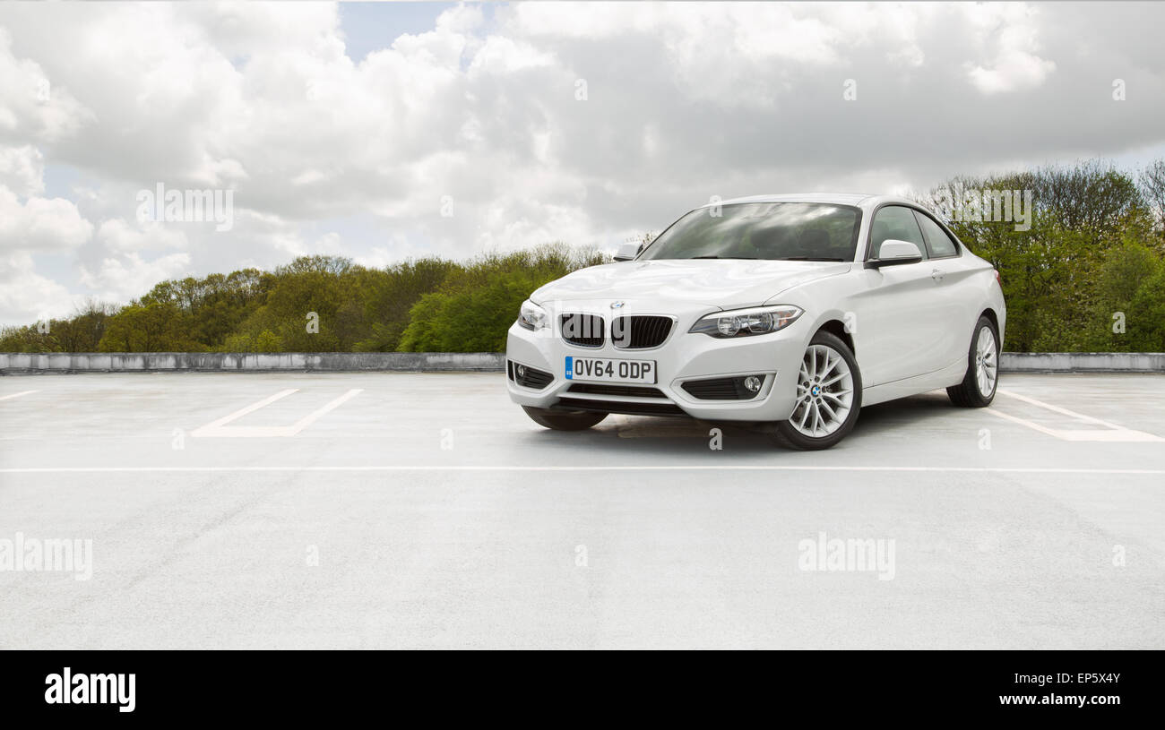 Una BMW 218d 2014 auto in bianco fotografati contro uno sfondo di alberi e blu cielo cloud. Foto Stock