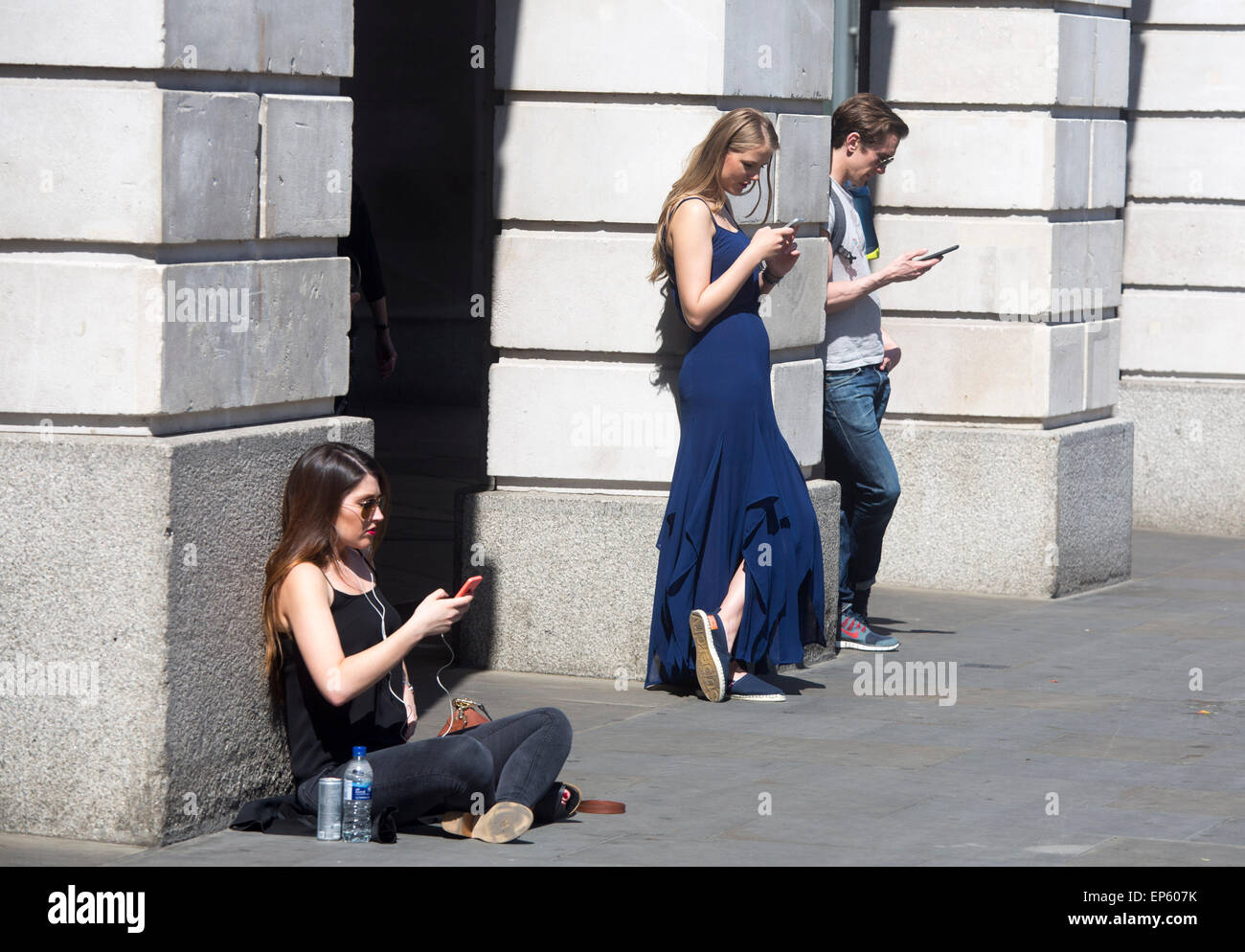 Iphone cellulare utenti utente di sole guardando i loro telefoni cellulari al di fuori dell'Apple Store in Covent Garden Foto Stock