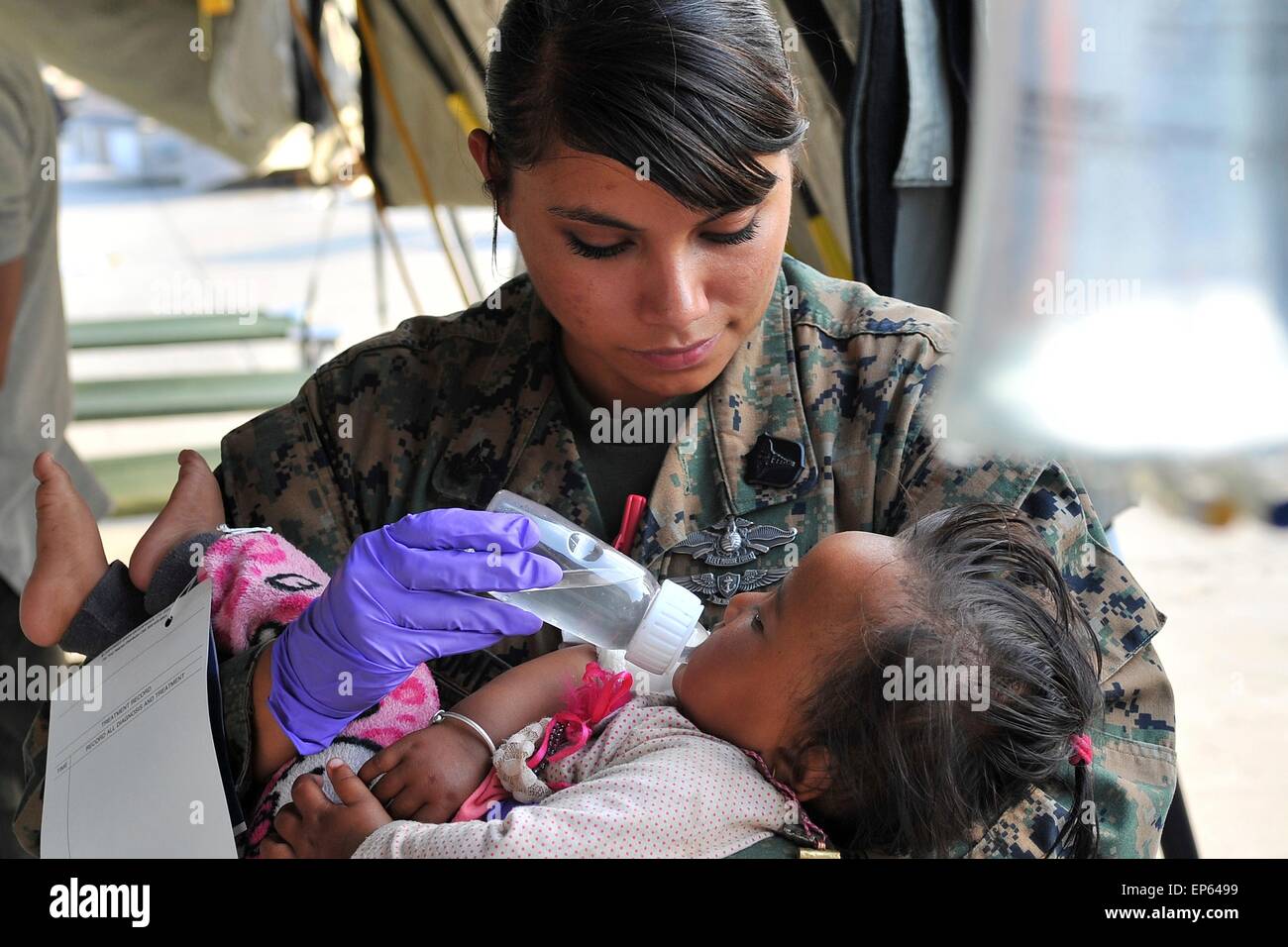 Kathmandu, Nepal. 13 Maggio, 2015. Stati Uniti Navy Petty Officer di 2a classe di Jessica Gomez-Hickman, Marine Attacco leggero elicottero Squadron 469 corpsman e Carey, Idaho, nativo, comfort un bambino vittima del terremoto a l'aeroporto internazionale di Tribhuvan di Kathmandu, Nepal, 12 maggio. Joint Task Force 505 membri lavorato con l'esercito nepalese di classificazione, il trattamento e il trasporto dei pazienti dopo un 7.3 grandezza terremoto ha colpito il 12 maggio a seguito di una grandezza 7.8 terremoto che ha devastato il Nepal Aprile 25. Foto Stock