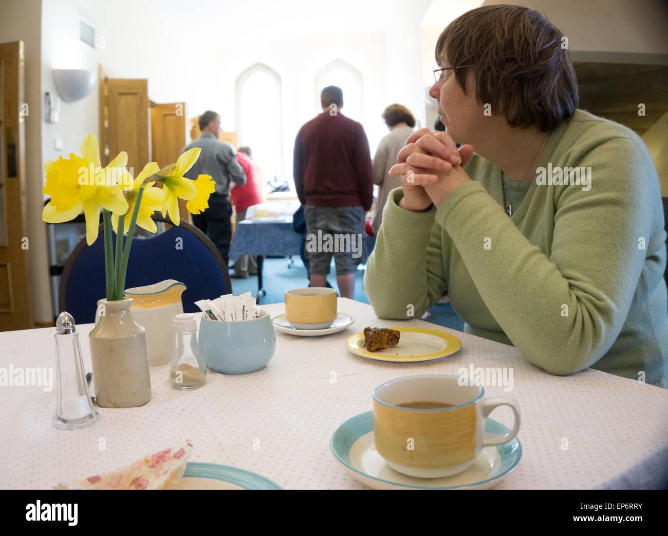 Donna con caffè e torta presso la chiesa infusioni Foto Stock