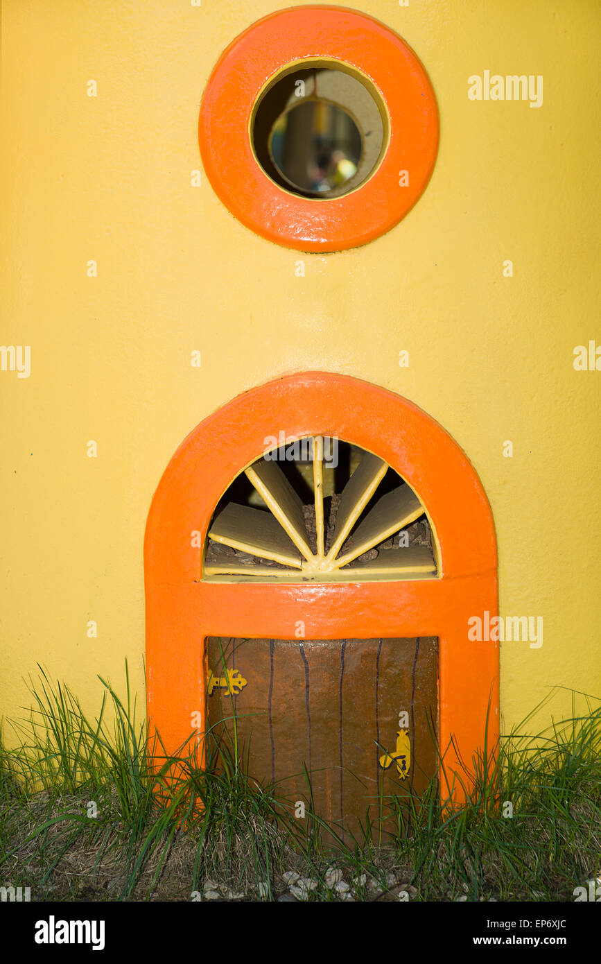 La piccola porta e finestra in una parete di colore giallo Foto Stock