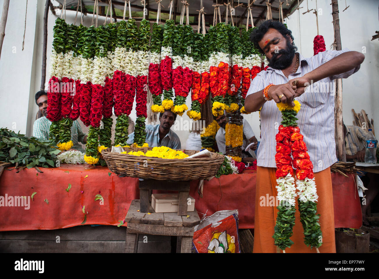 L'uomo fare ghirlande per la vendita presso il mercato dei fiori in Tirupati Foto Stock