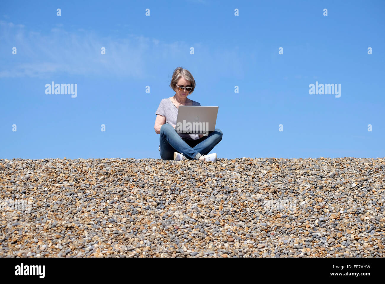Senior donna utilizzando il computer portatile sulla spiaggia Foto Stock