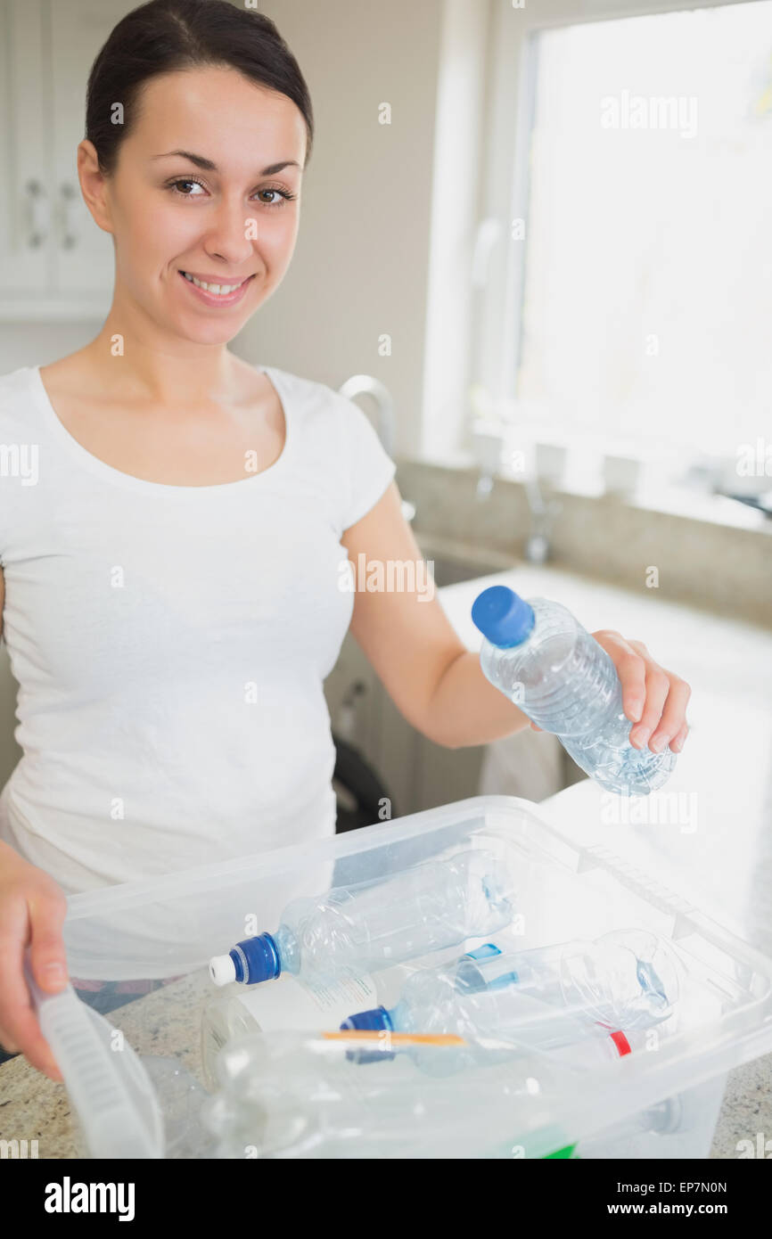 Donna gettando molte bottiglie in contenitore di riciclaggio Foto Stock