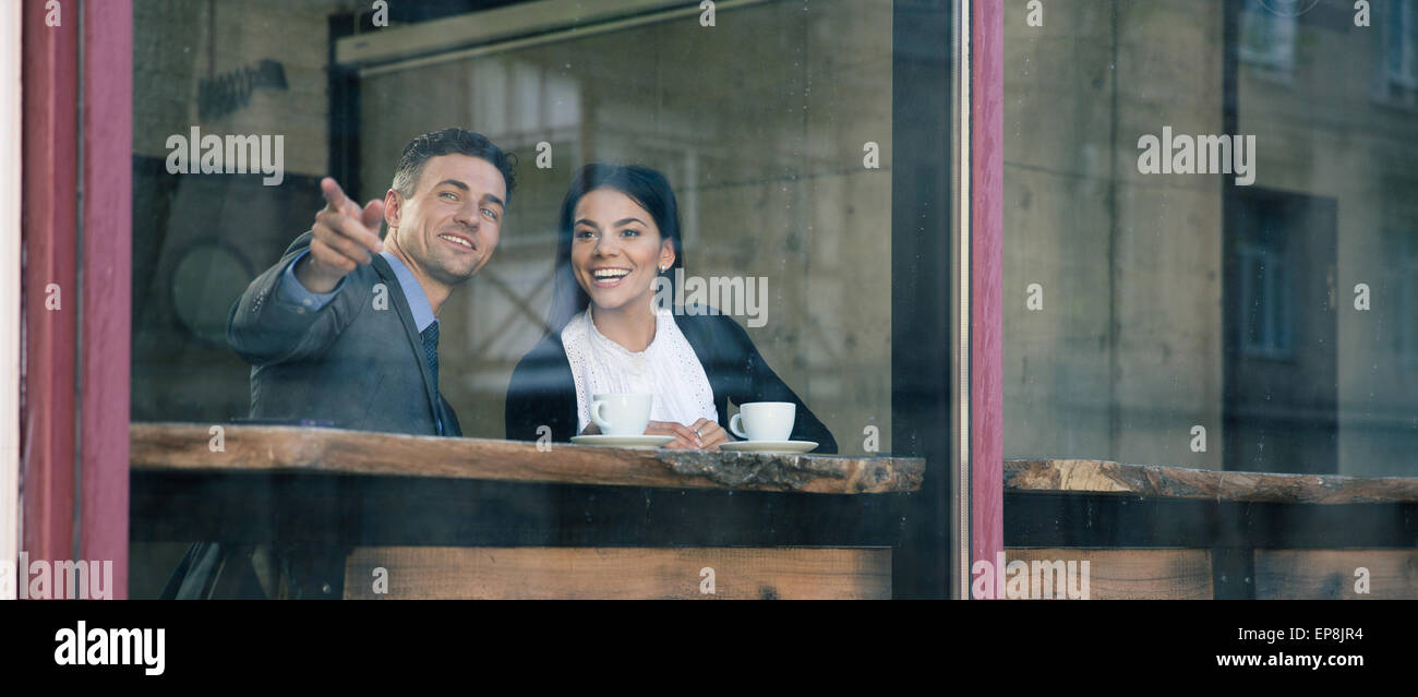 Happy businessman puntando su qualcosa in cafe Foto Stock
