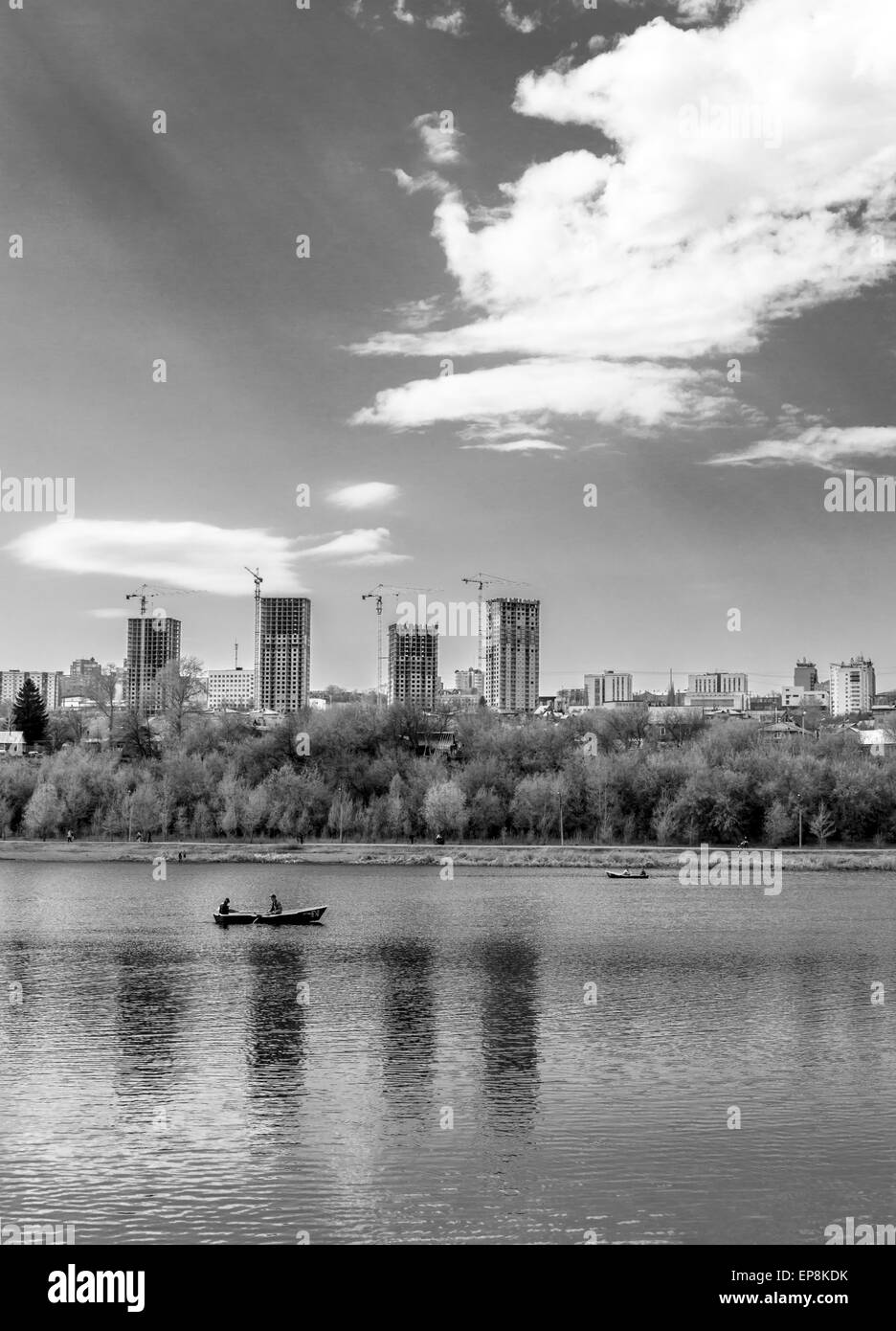Unica barca a remi su un lago con alto edificio di appartamenti in bianco e nero Foto Stock