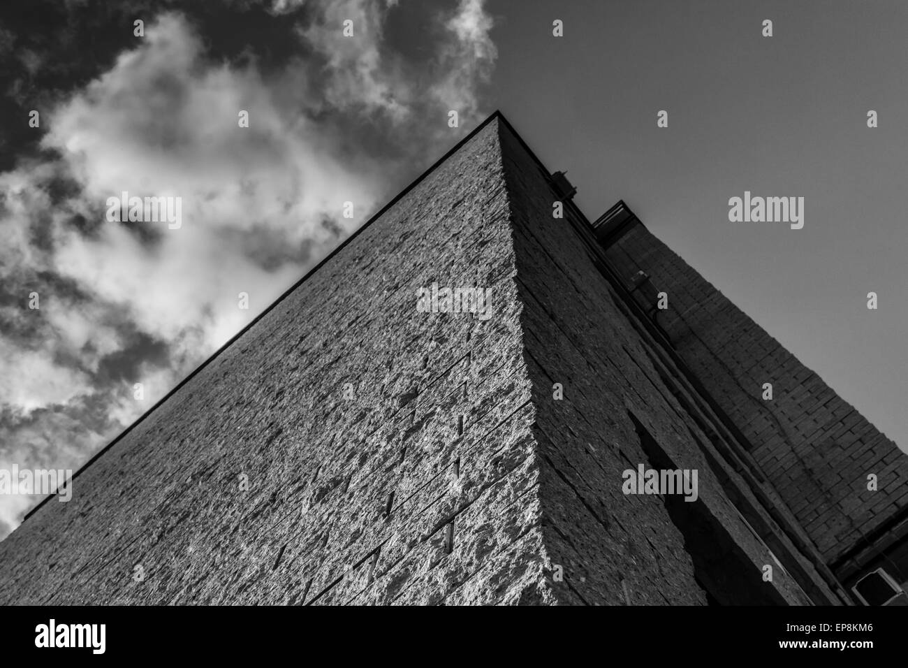 E moderno grattacielo costruito con bordi taglienti contro un cielo nuvoloso in bianco e nero Foto Stock